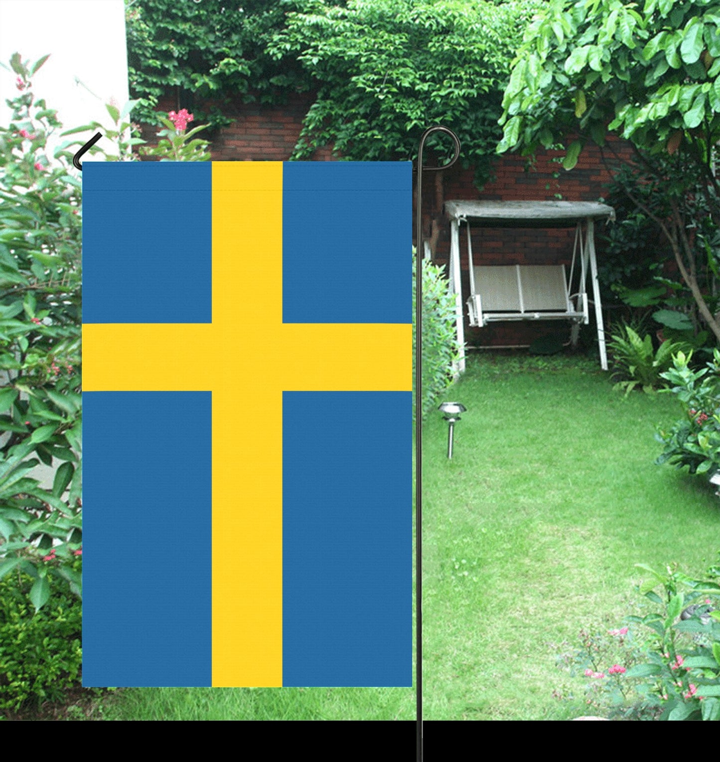Luv My Flag Swedish garden flag displayed in lush garden.