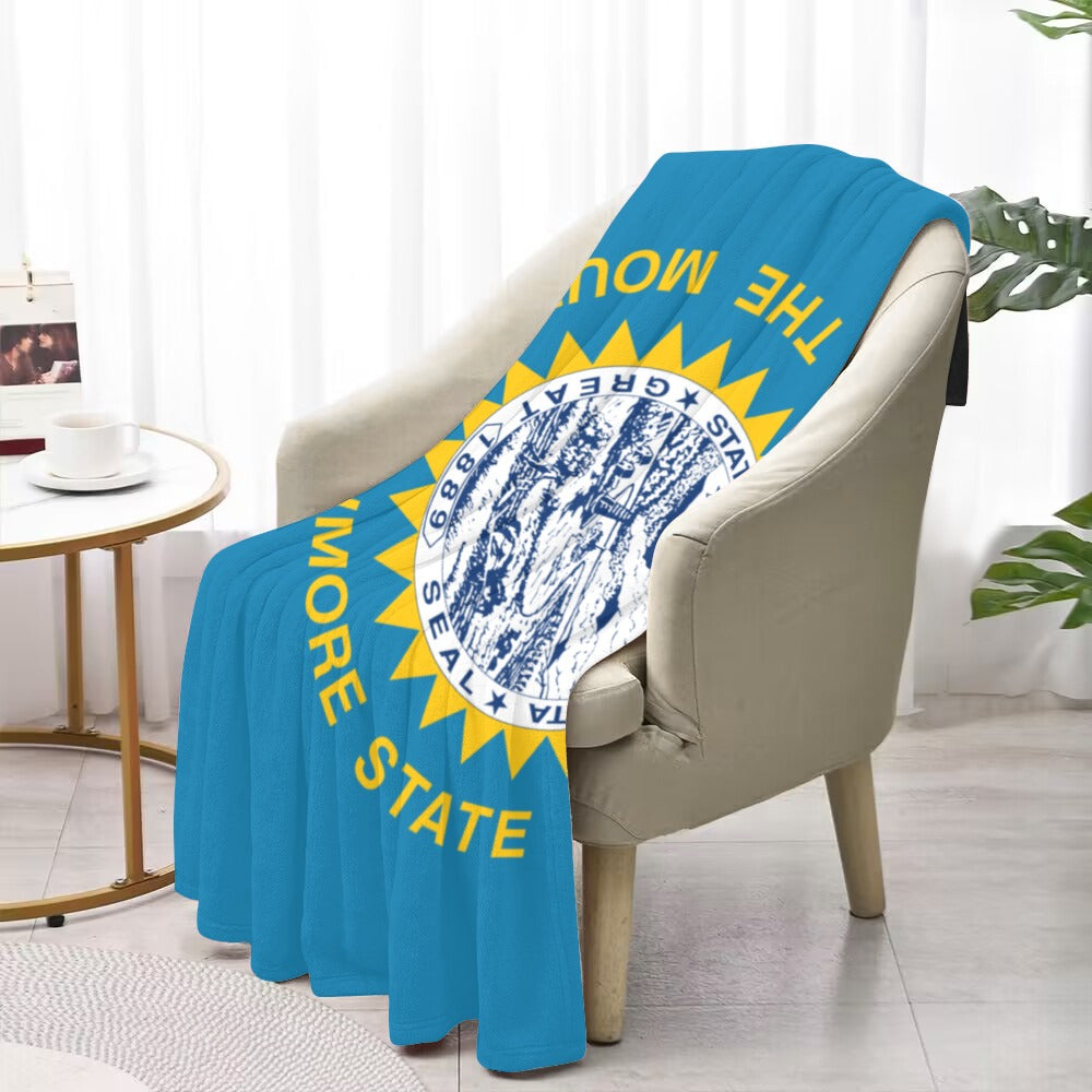 Blue "Luv My Flag" blanket draped over beige chair.