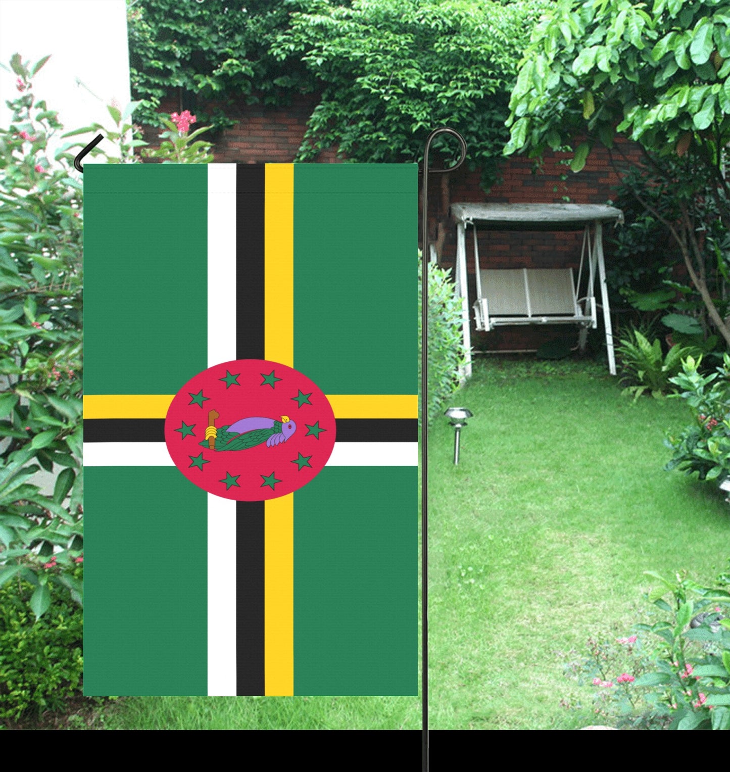 Luv My Flag's Dominica flag displayed in green garden.