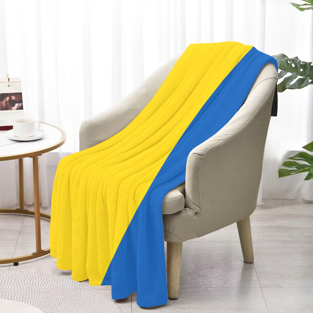 Cozy armchair draped with Luv My Flag yellow-blue blanket.