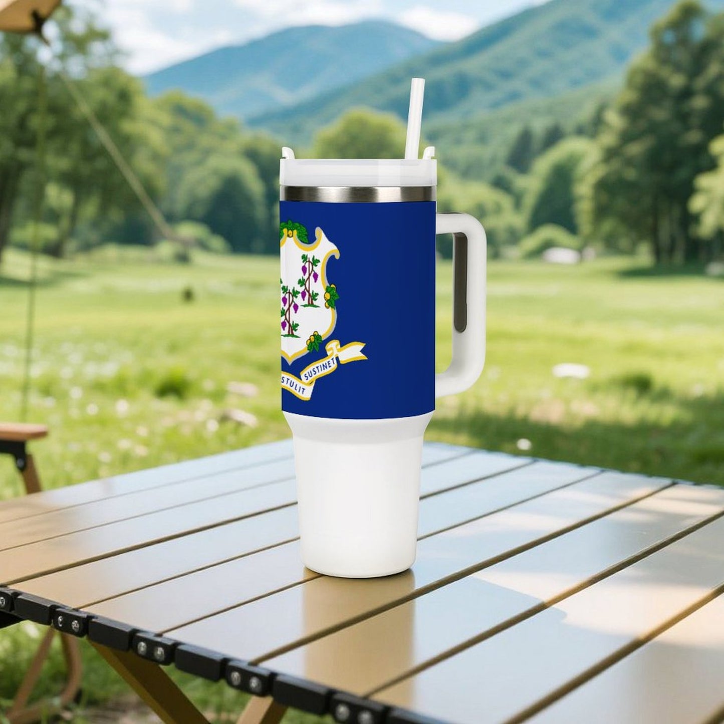 Brand tumbler on table with scenic mountain background, outdoors.