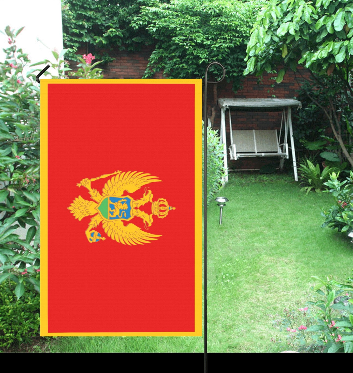Red flag with emblem displayed in a garden. Luv My Flag.