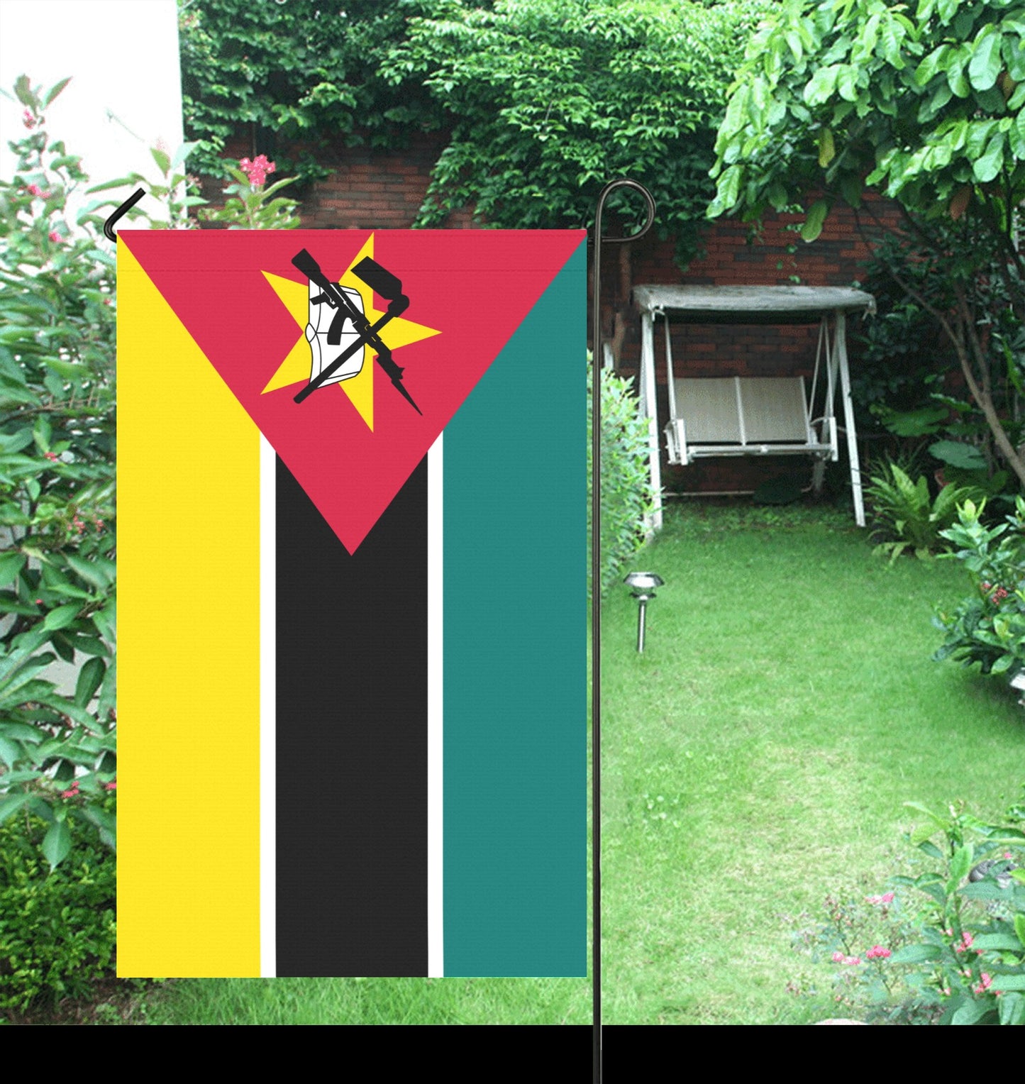 Luv My Flag Mozambique garden flag displayed in lush garden.