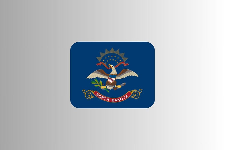 North Dakota state flag with a dark blue field featuring a bald eagle holding arrows and an olive branch, a red ribbon reading “North Dakota,” and a shield with a fan of stars above the eagle.