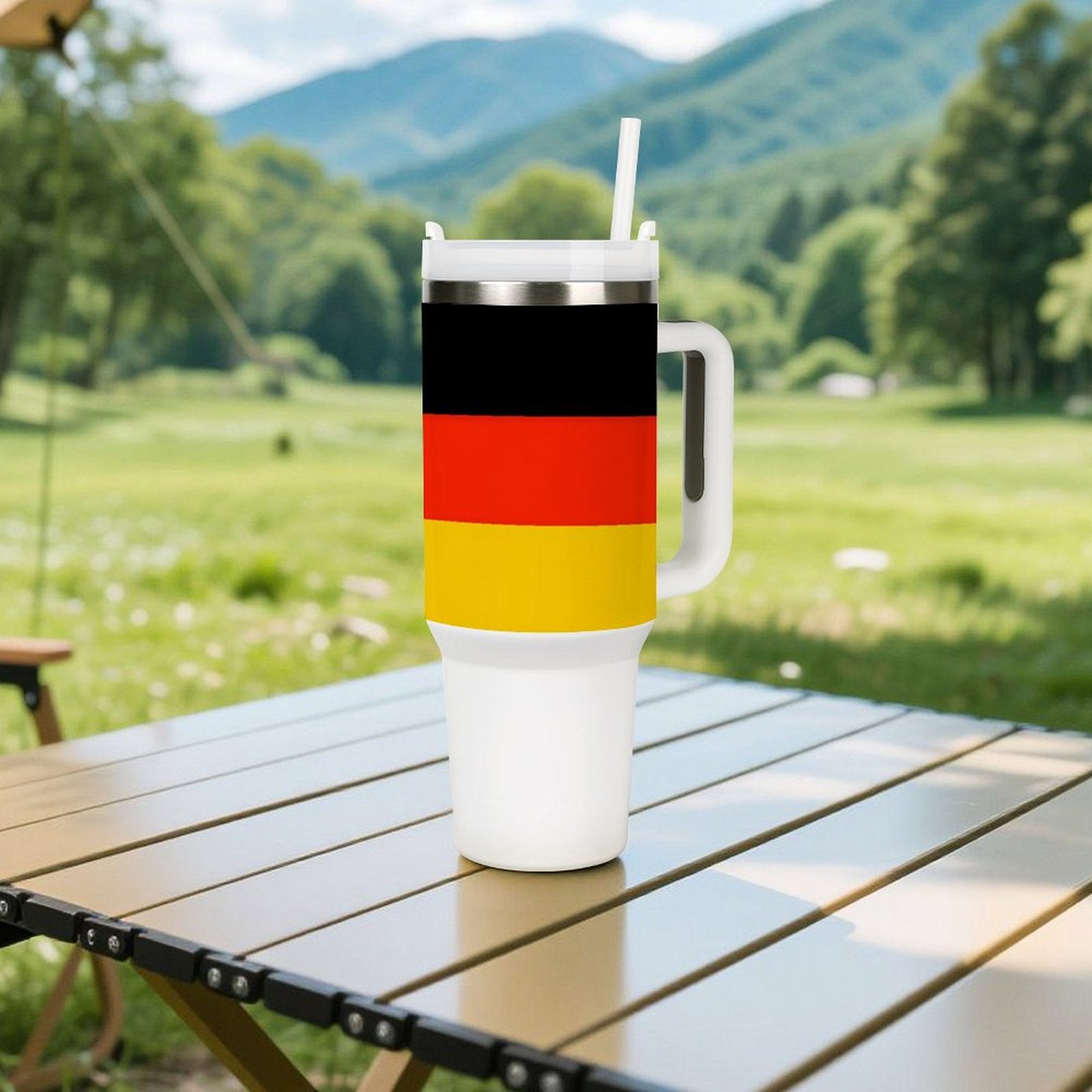 [Brand] travel mug with German flag on picnic table.
