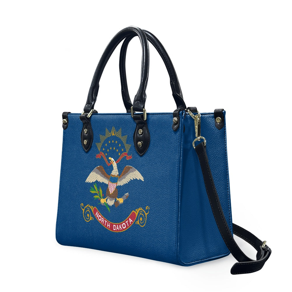 [Brand] blue handbag with North Dakota emblem, black handles.