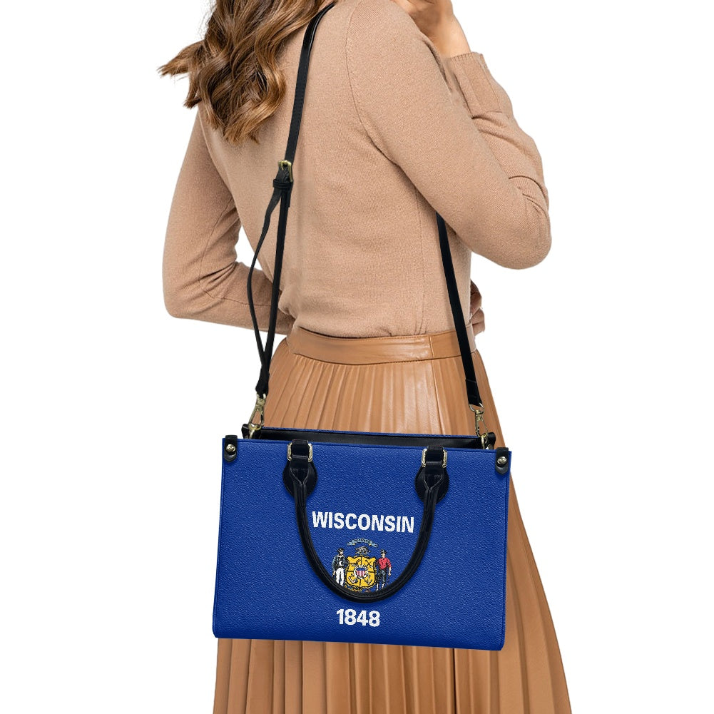 Woman holding [Brand] blue Wisconsin-themed shoulder bag confidently.