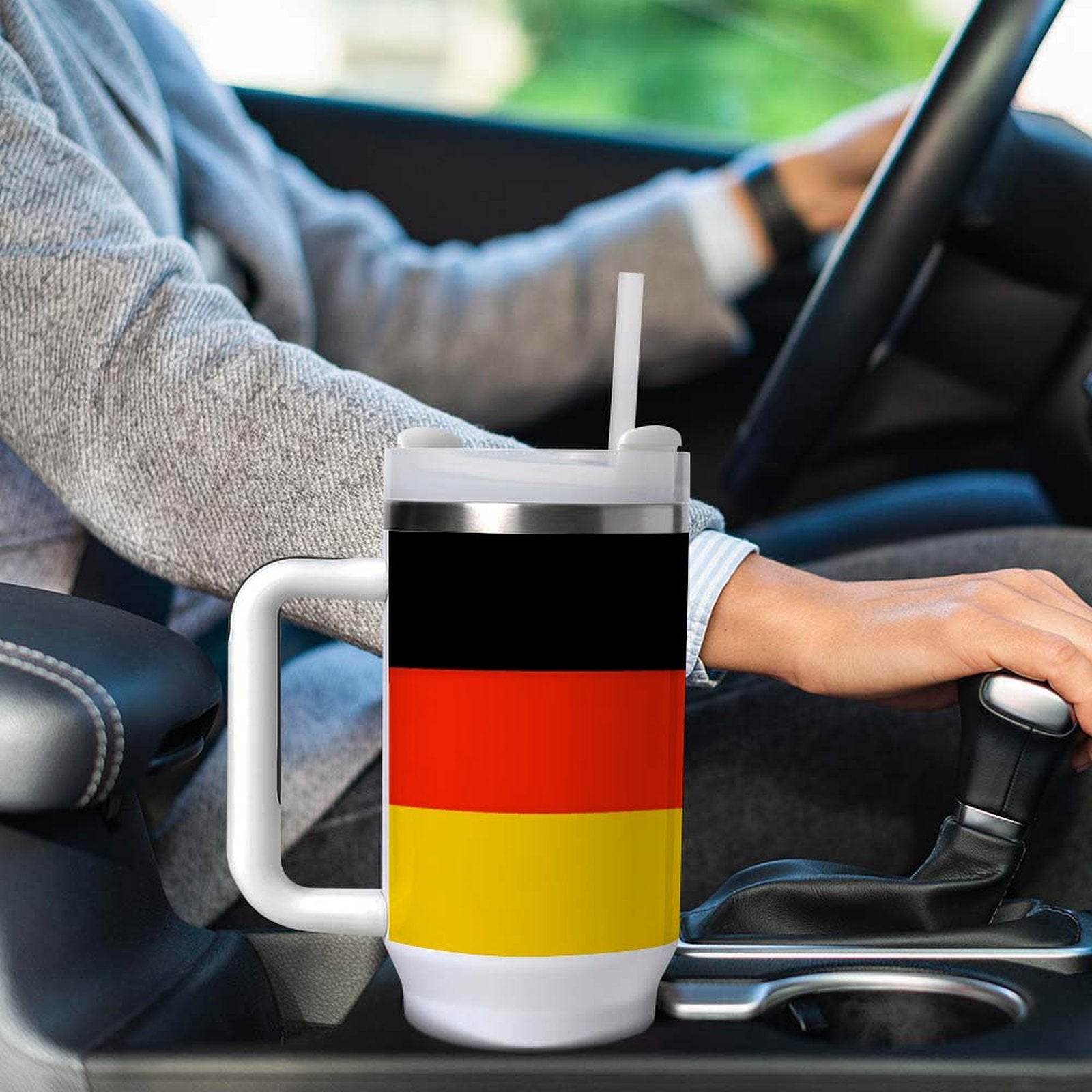 Person driving with [Brand] cup featuring German flag design.