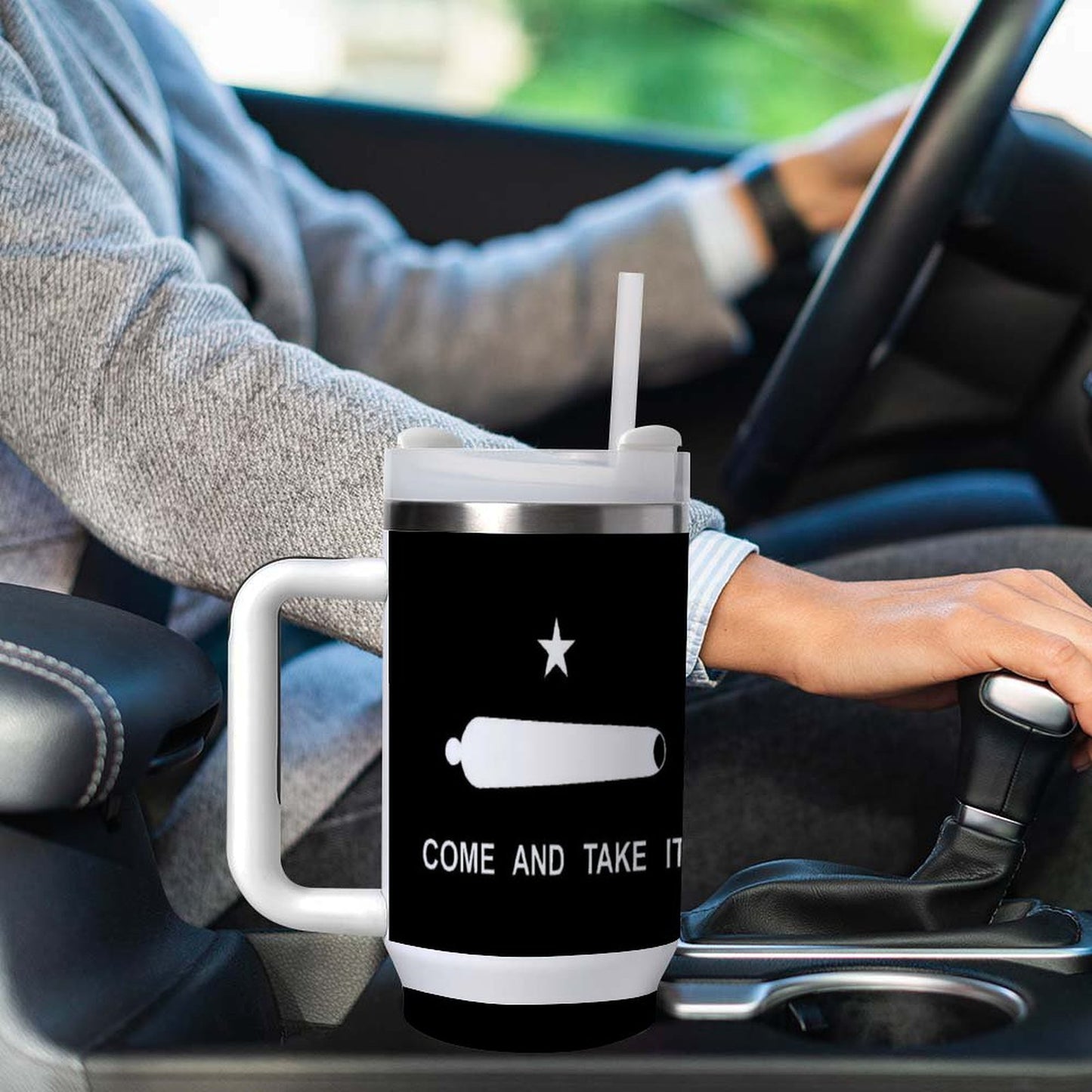 Person drives while holding [Brand] mug with bold text.