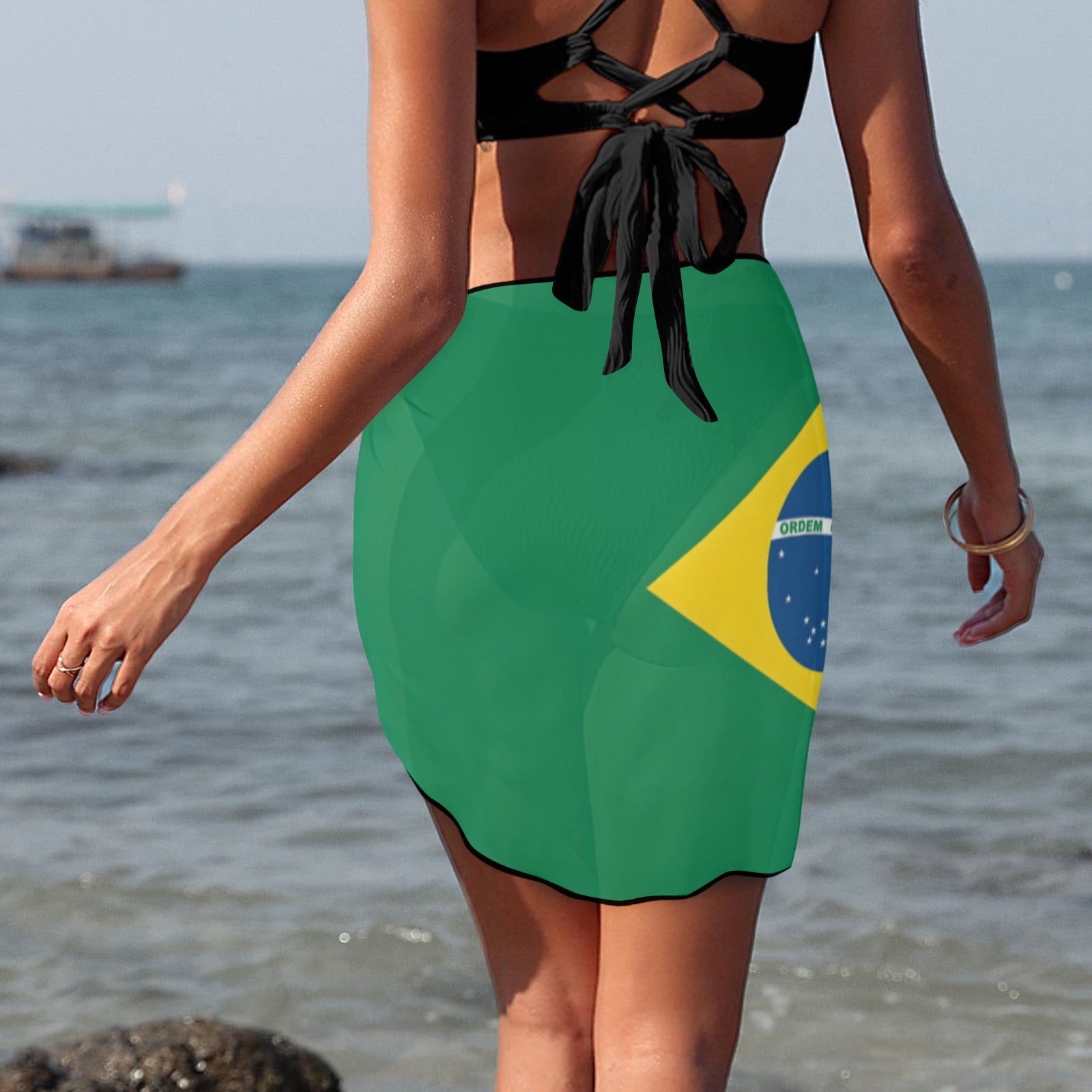 Woman at beach wearing [Brand] dress featuring Brazilian flag.