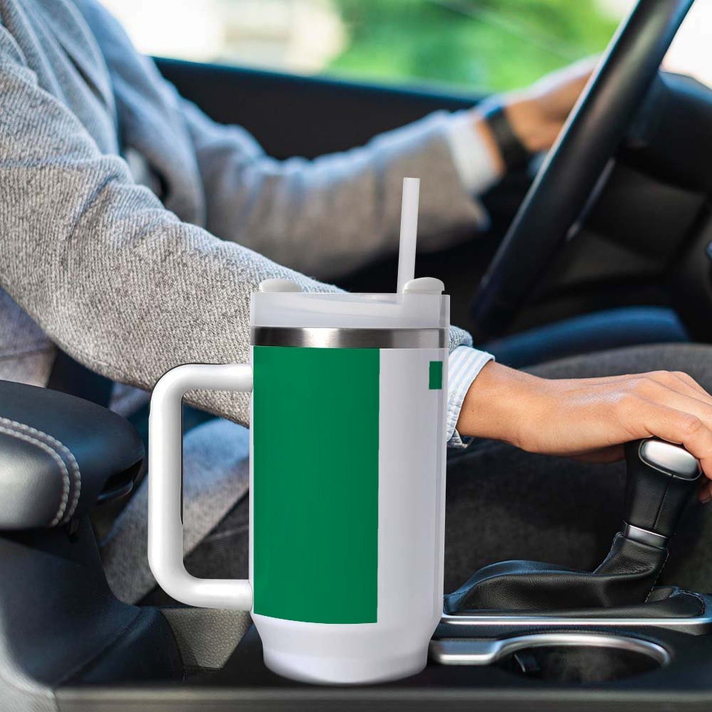 Driver using [Brand] green mug with straw in car.