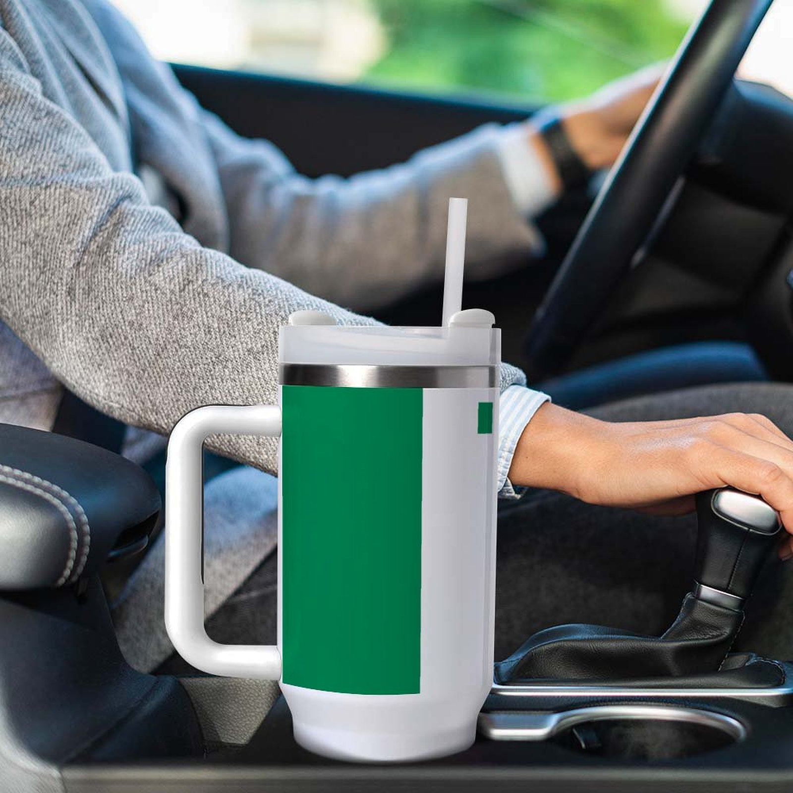 Driver using [Brand] green mug with straw in car.