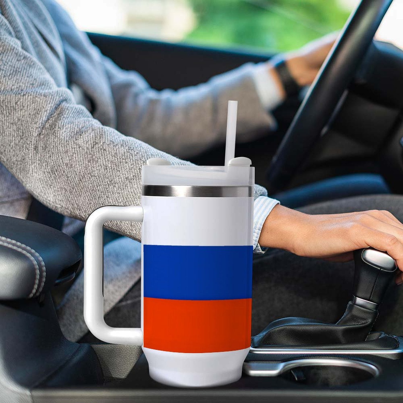 Person driving with [Brand] patriotic mug in car holder.