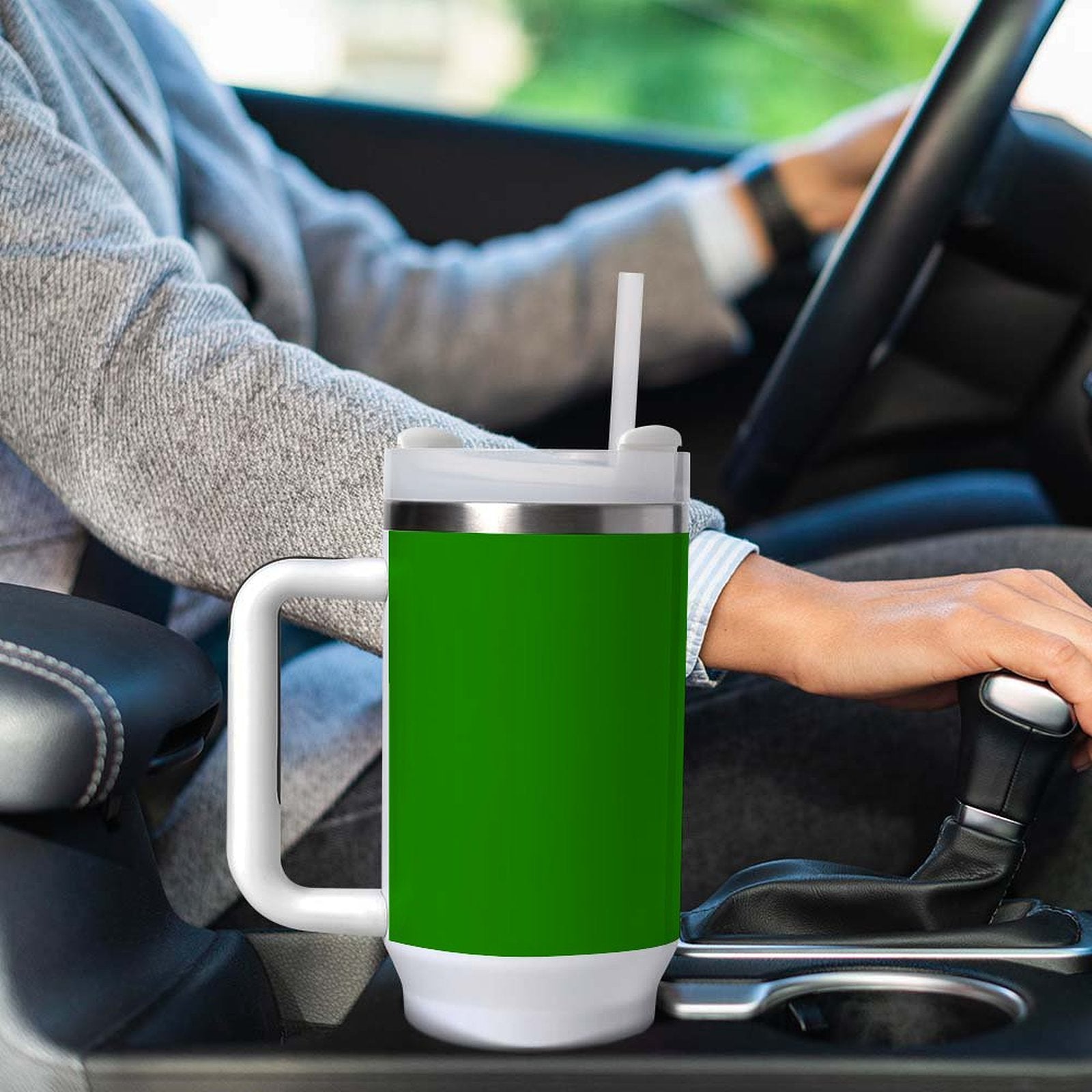 Driver holding gearshift with [Brand] green travel mug nearby.