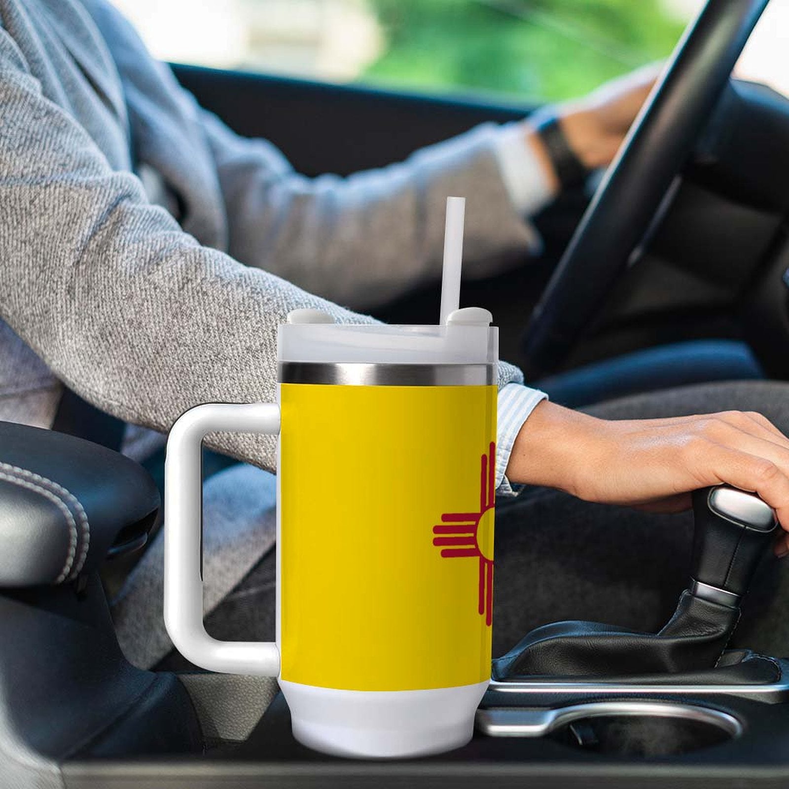 Person driving with [Brand] yellow cup in car holder.