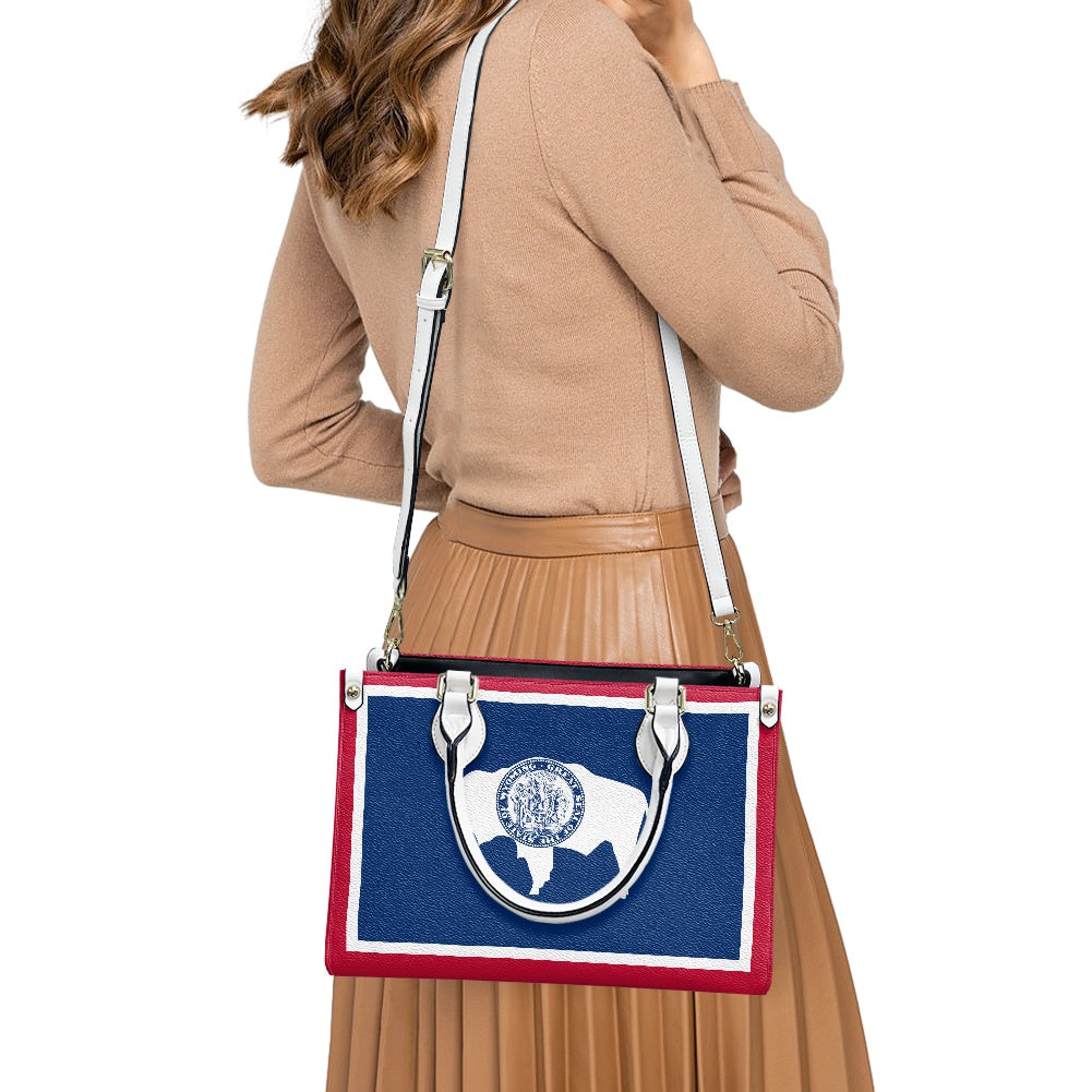 Woman carrying [Brand] handbag with blue and red design.