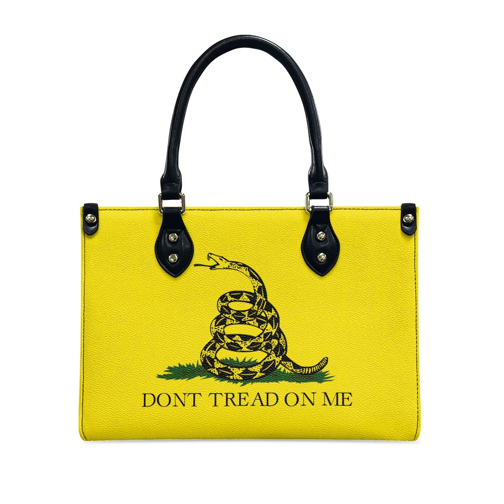 Yellow [Brand] handbag with snake graphic, black handles.