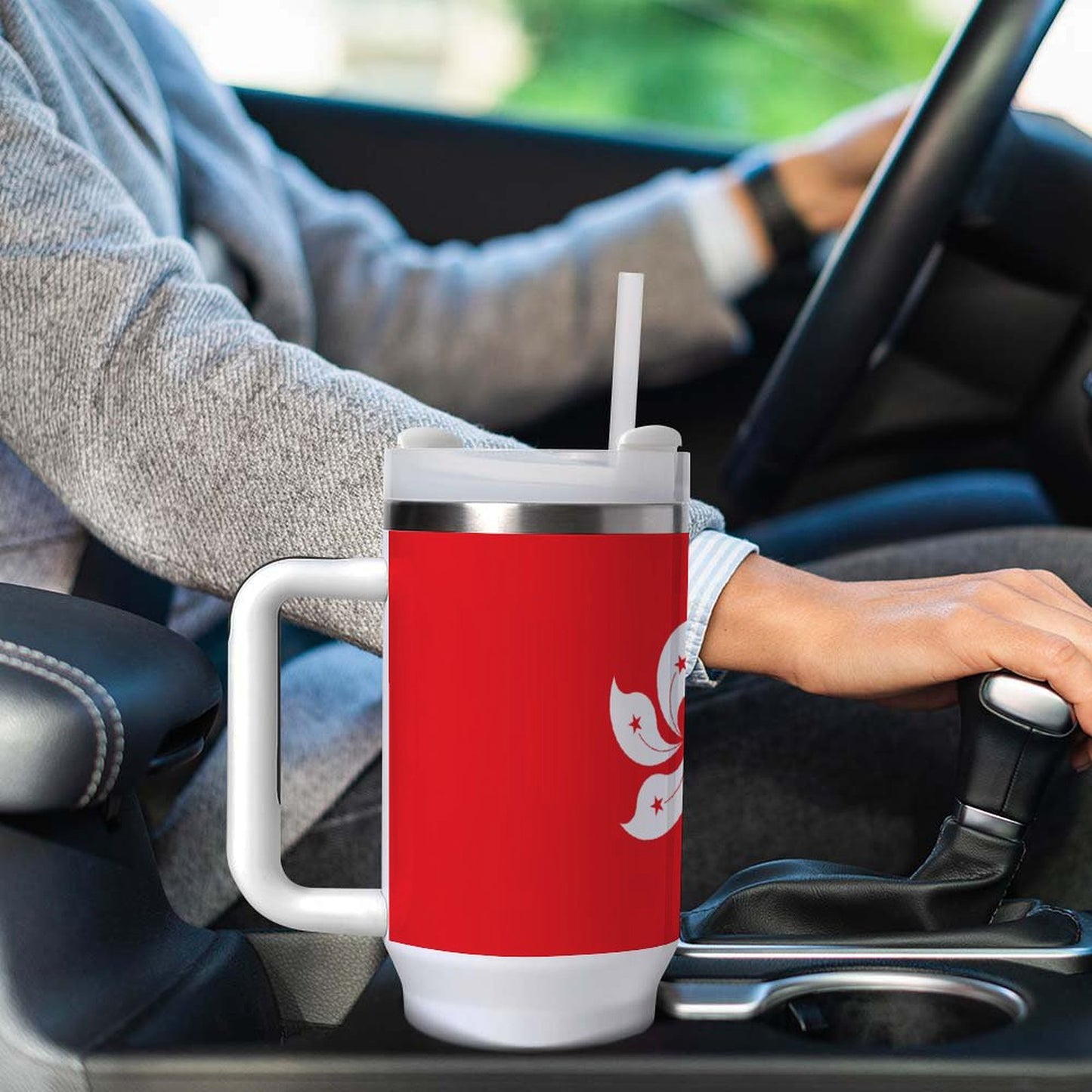 Person driving car with red [Brand] mug, straw visible.
