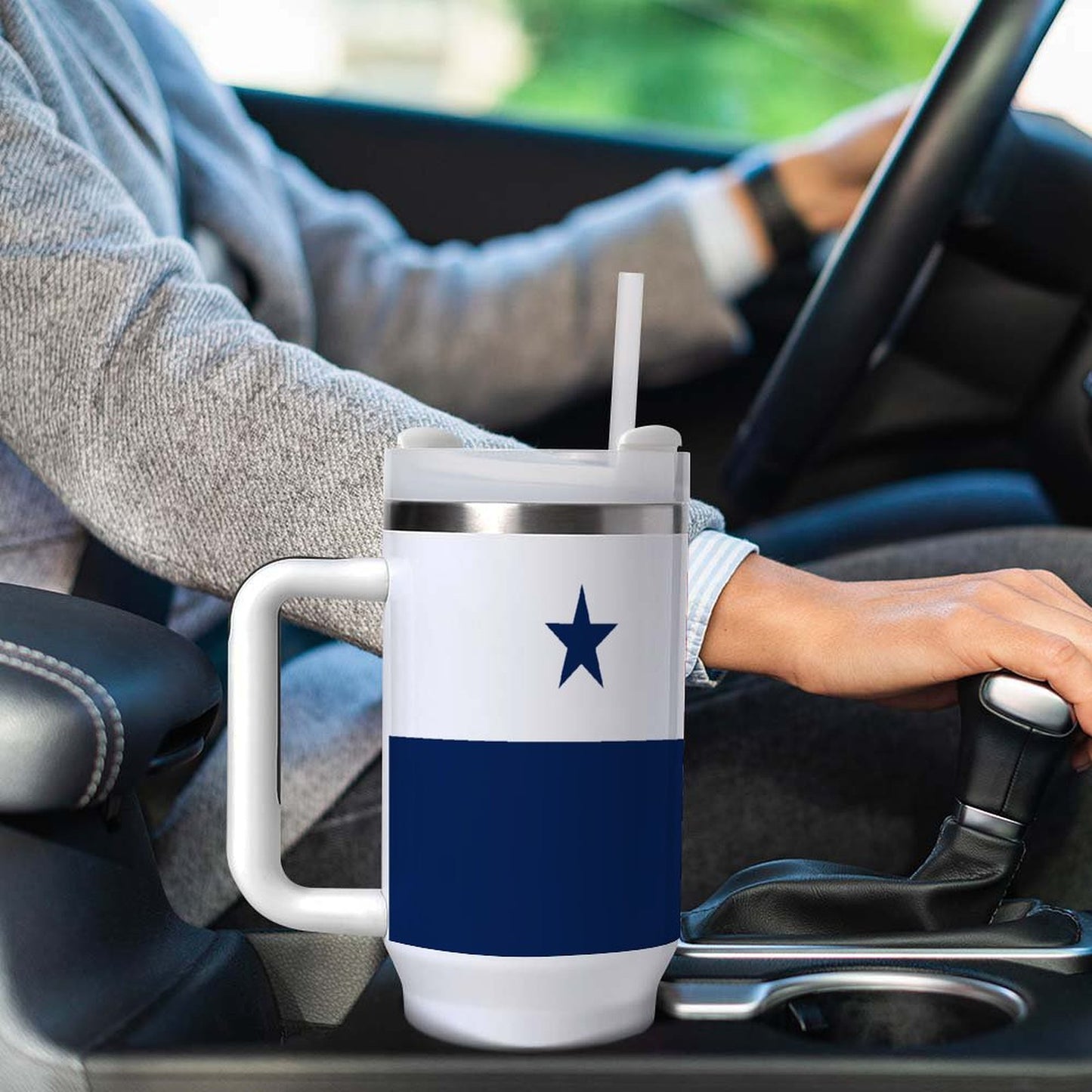 Person driving with [Brand] travel mug in car holder.