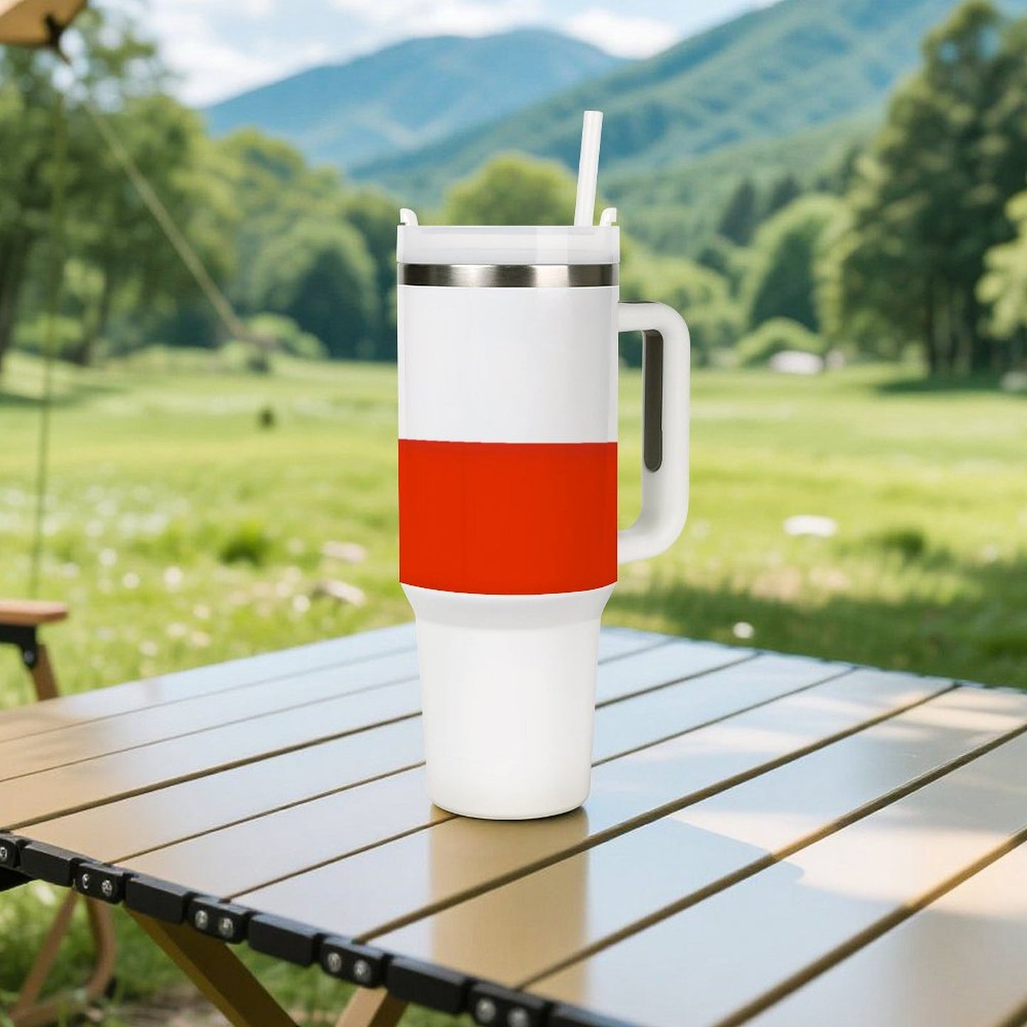 [Brand] insulated mug with straw on outdoor table, mountains behind.