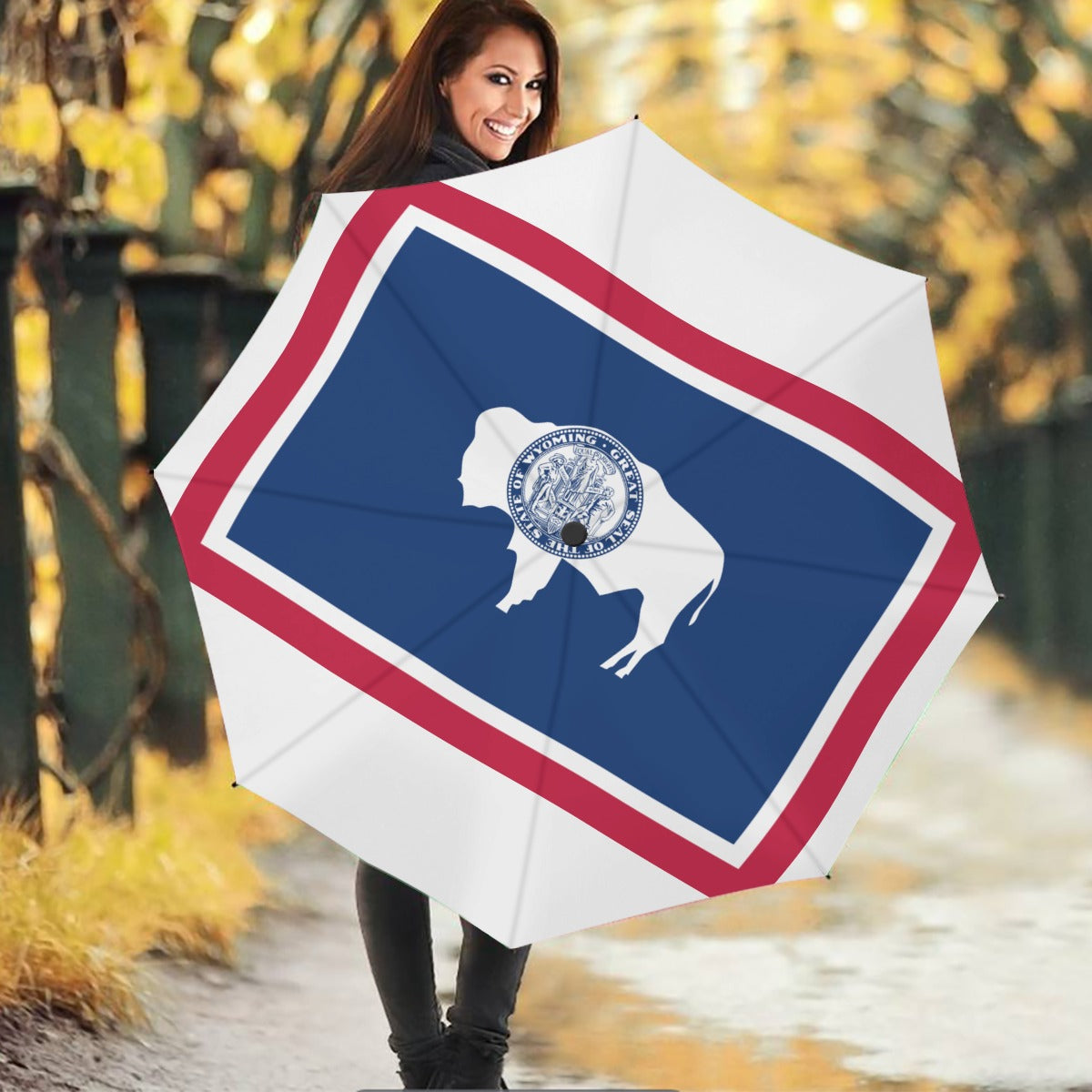 Smiling woman holding [Brand] Wyoming flag umbrella outdoors.