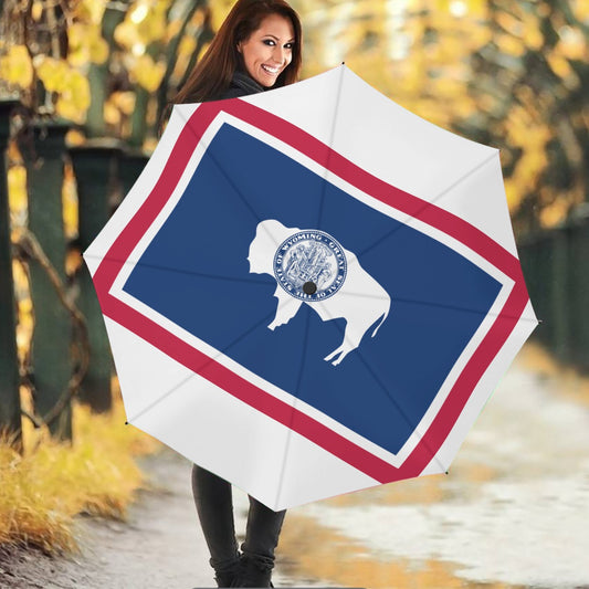 Smiling woman holding [Brand] Wyoming flag umbrella outdoors.