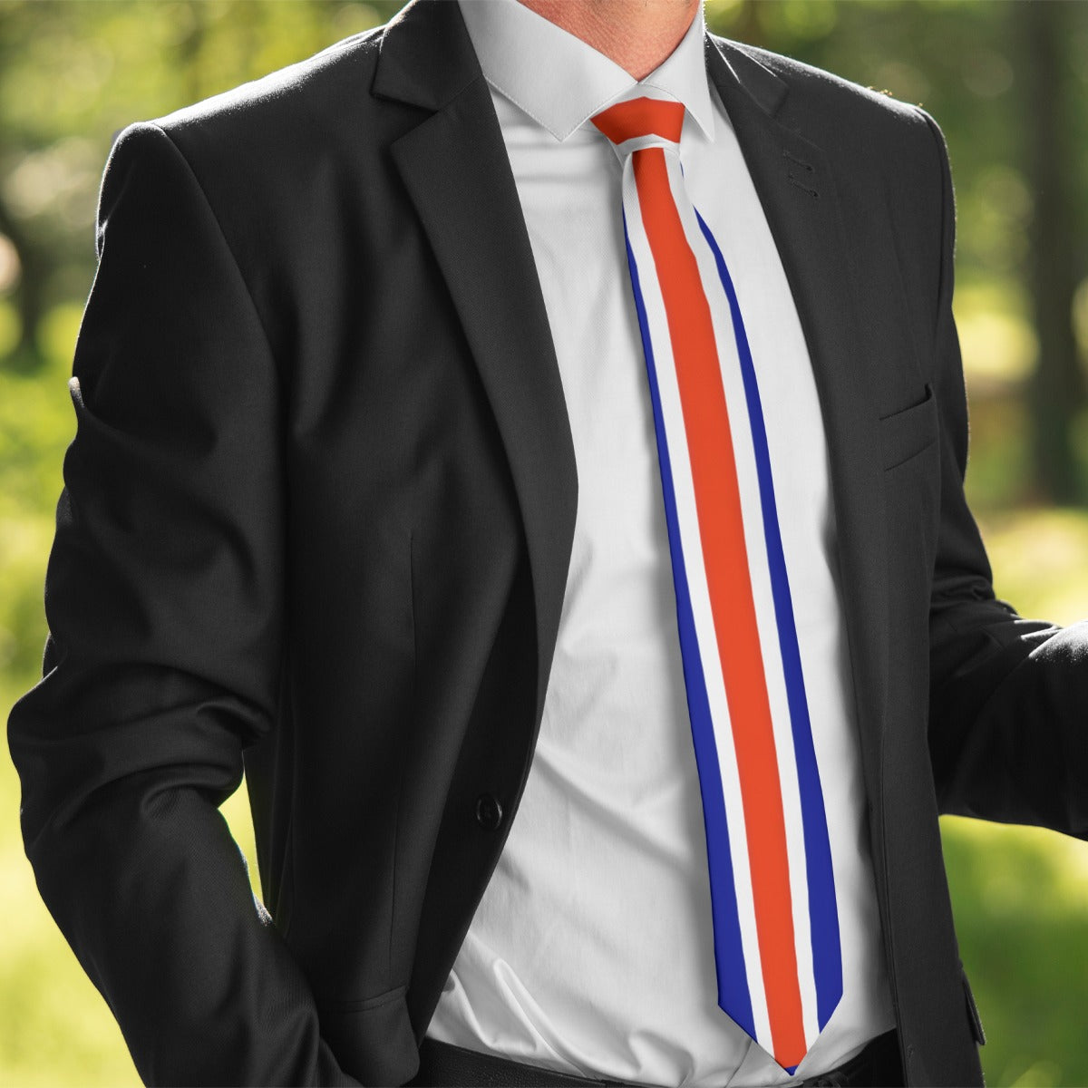 Man in black suit with colorful [Brand] tie outdoors.