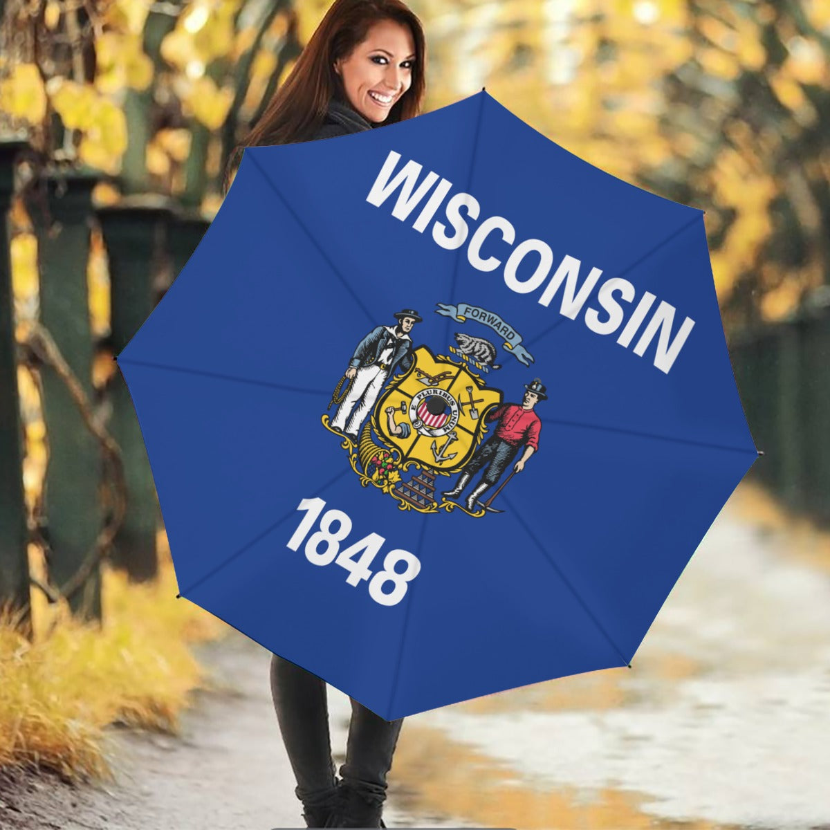 Smiling woman holding [Brand] Wisconsin-themed umbrella on pathway.