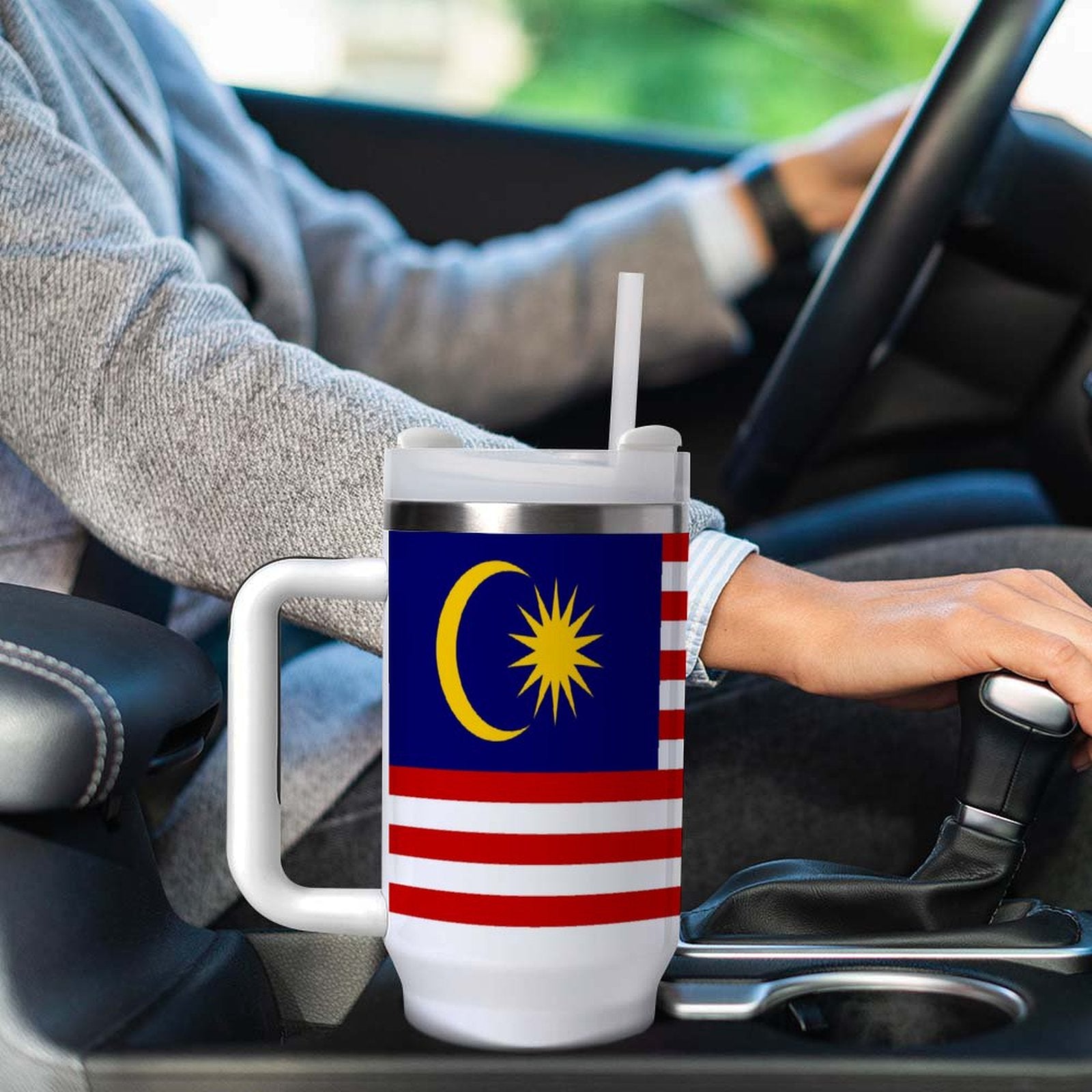 A [Brand] travel mug with Malaysian flag design in car.