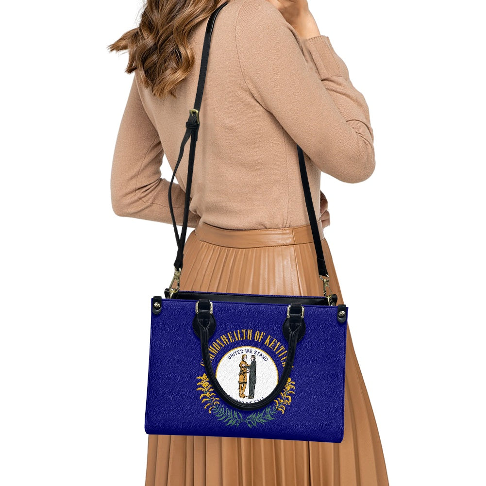 Woman carrying [Brand] blue Kentucky-themed handbag, wearing skirt.