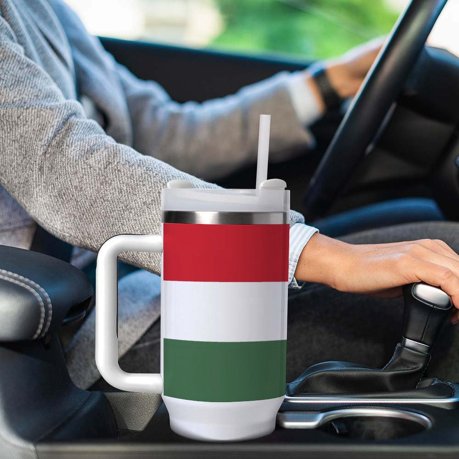 Person driving with [Brand] travel mug in car holder.