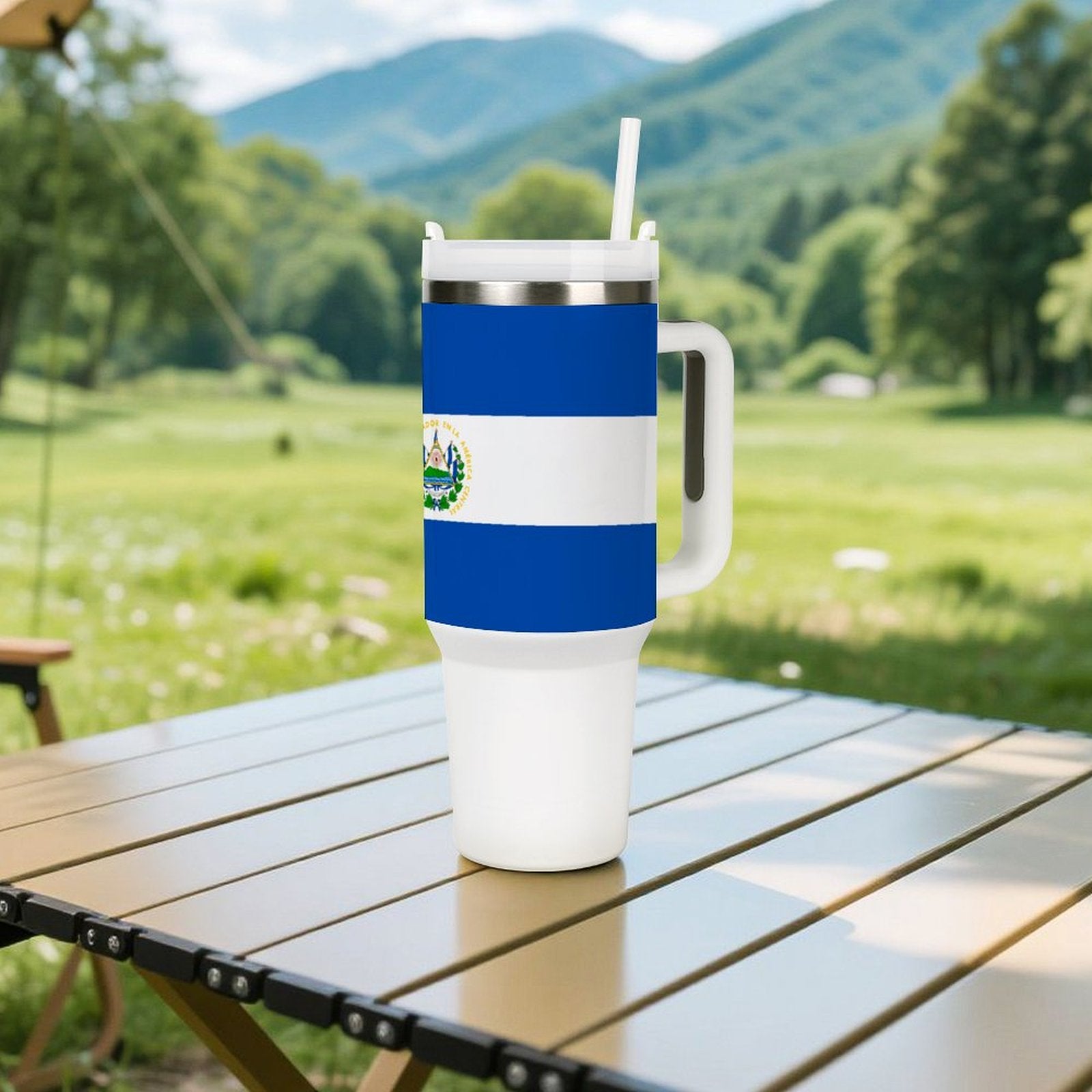 Travel mug with El Salvador flag on outdoor table. [Brand]