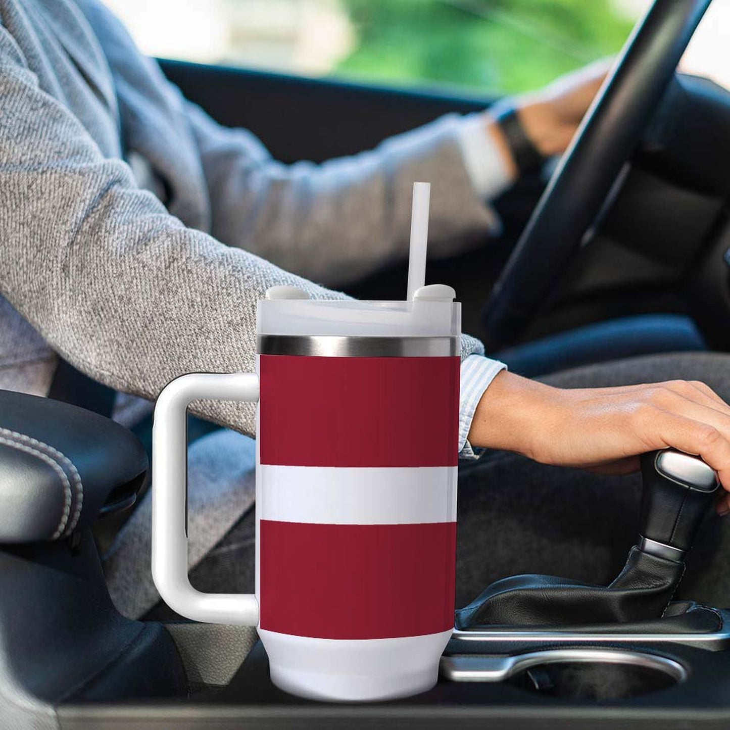 A red-and-white [Brand] travel mug in a car.