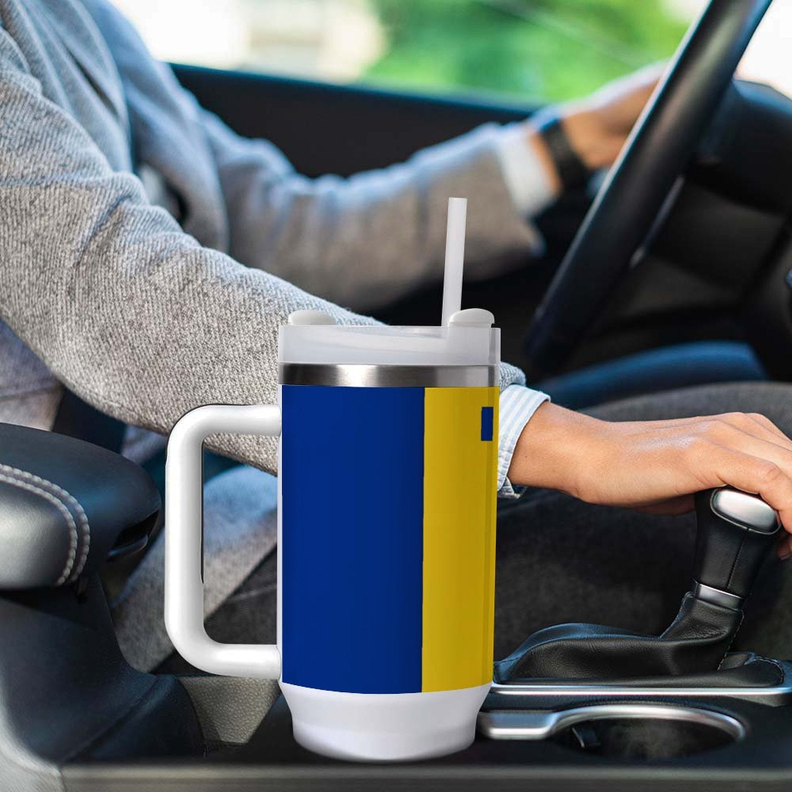 Driver with [Brand] mug in car, blue and yellow design.