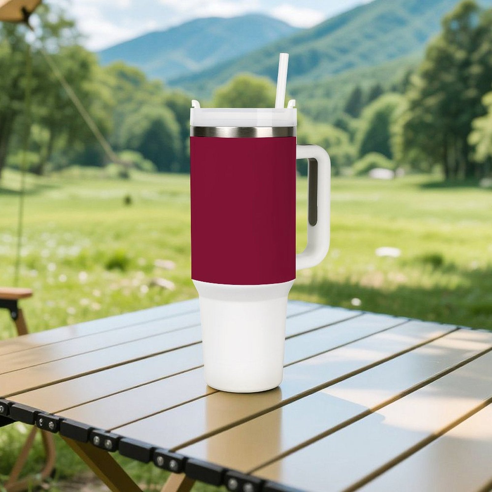 [Brand] burgundy travel mug with straw on outdoor table.