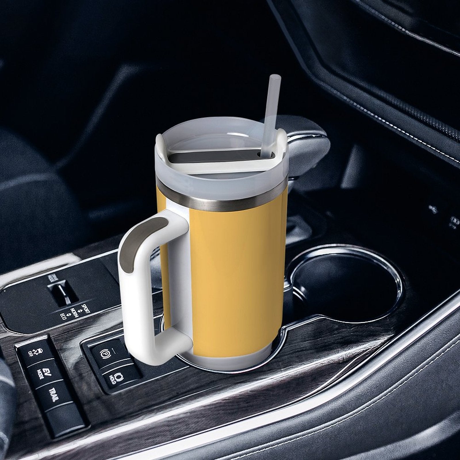 Yellow [Brand] travel mug with straw in car cup holder.