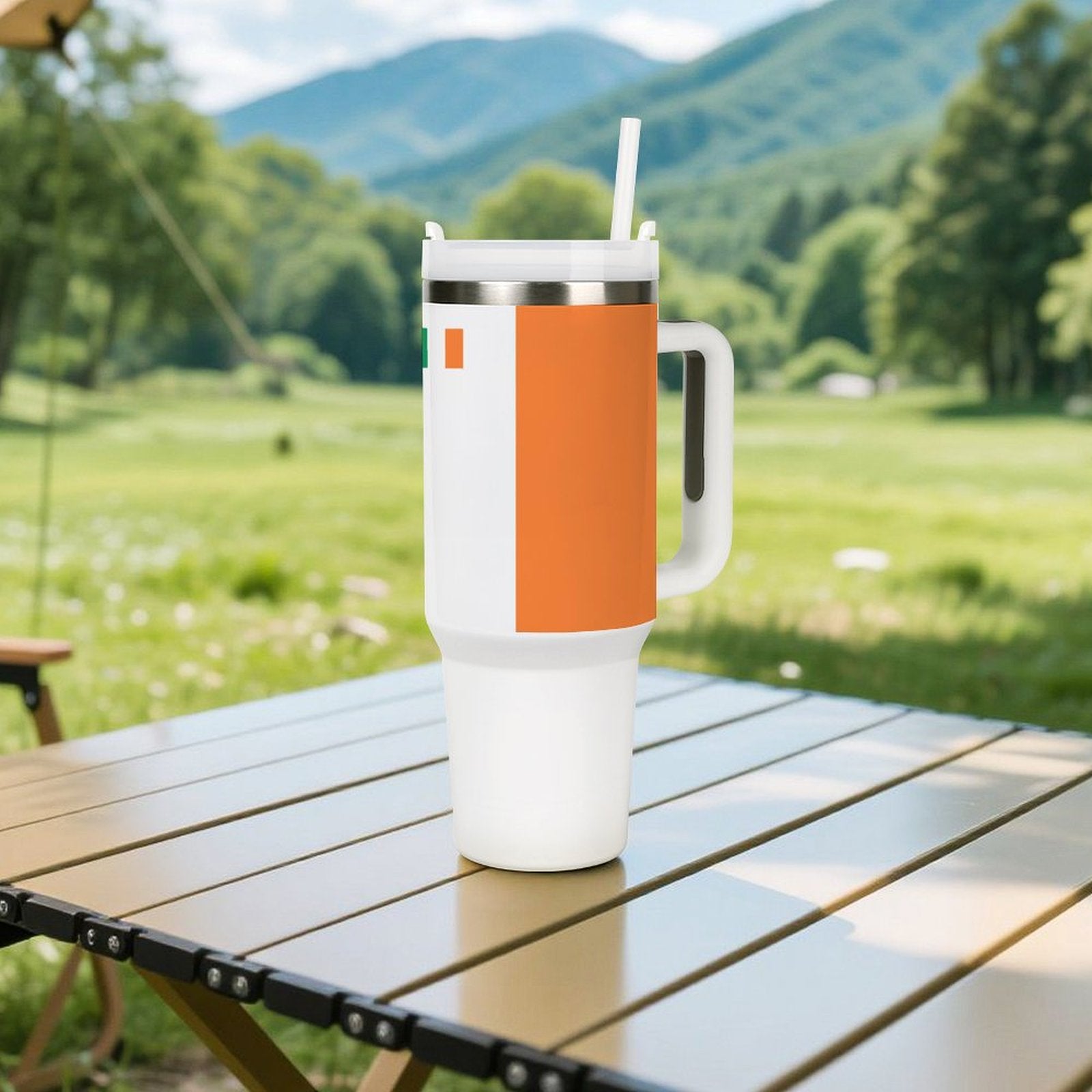 [Brand] mug with orange design on outdoor table, mountains.