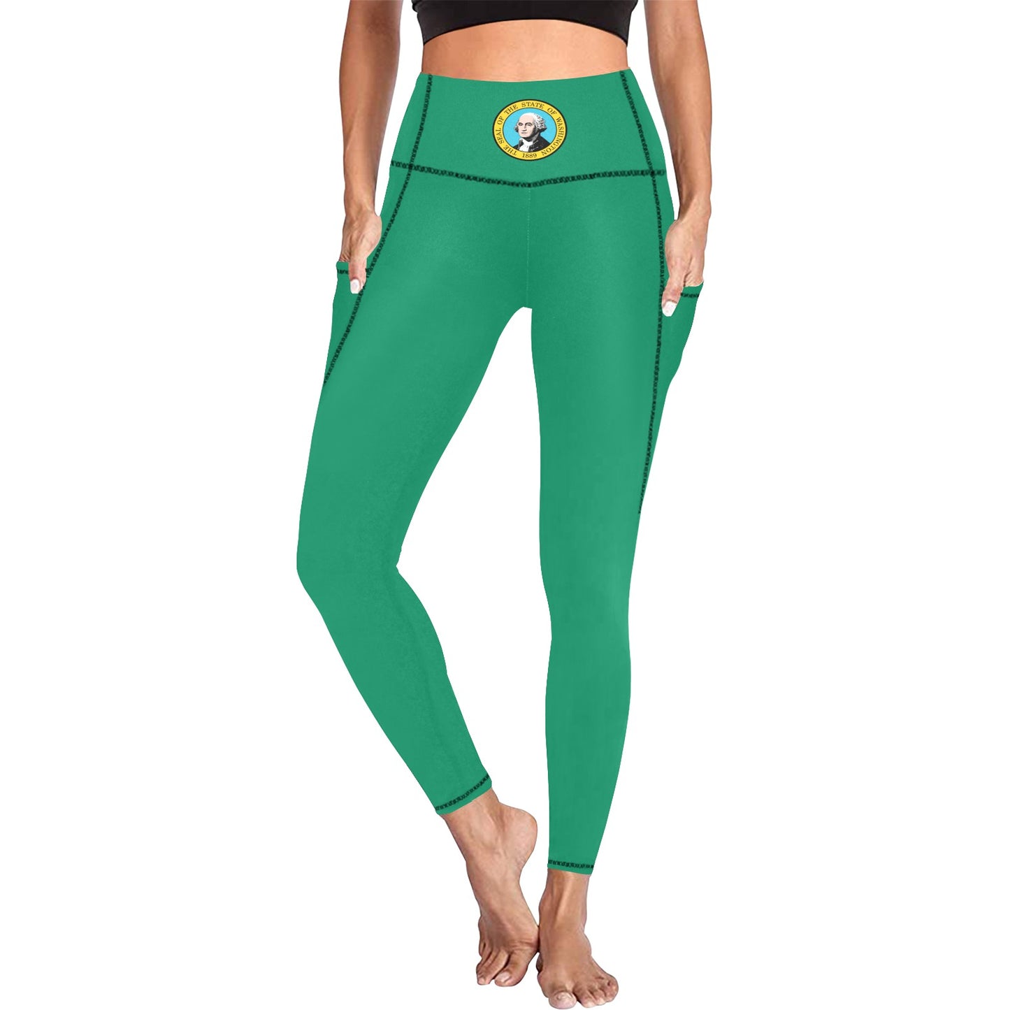 A woman wearing green leggings with her hands in the pockets.  The leggings have George Washington, the state of Washington seal on the waist