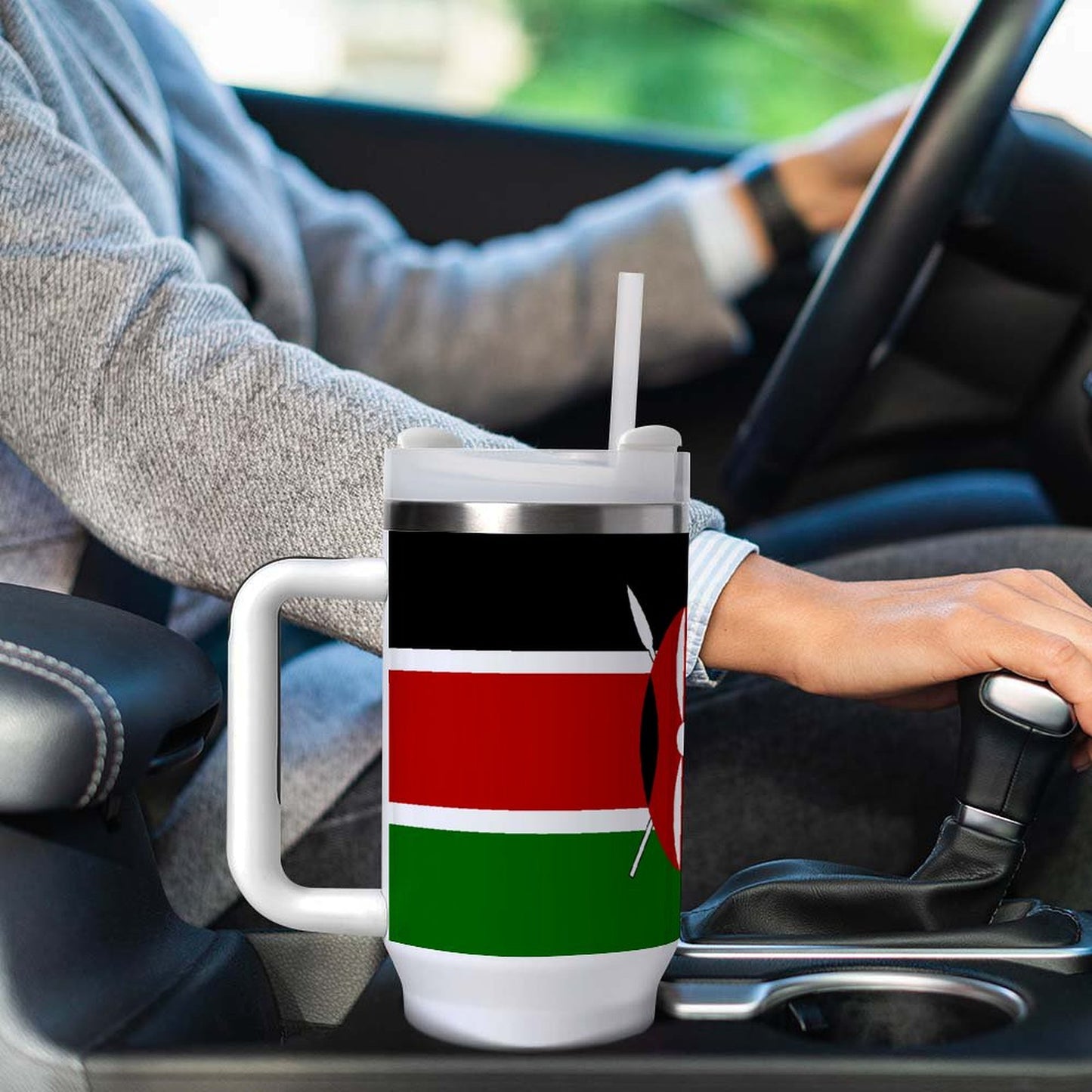 Person drives holding [Brand] mug with Kenyan flag design.