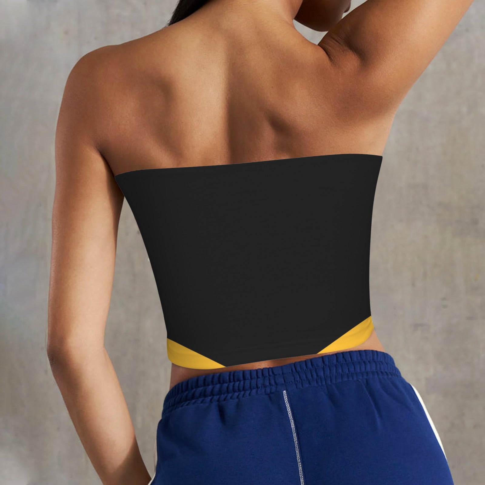 Woman wearing black [Brand] top, blue shorts, gray background.