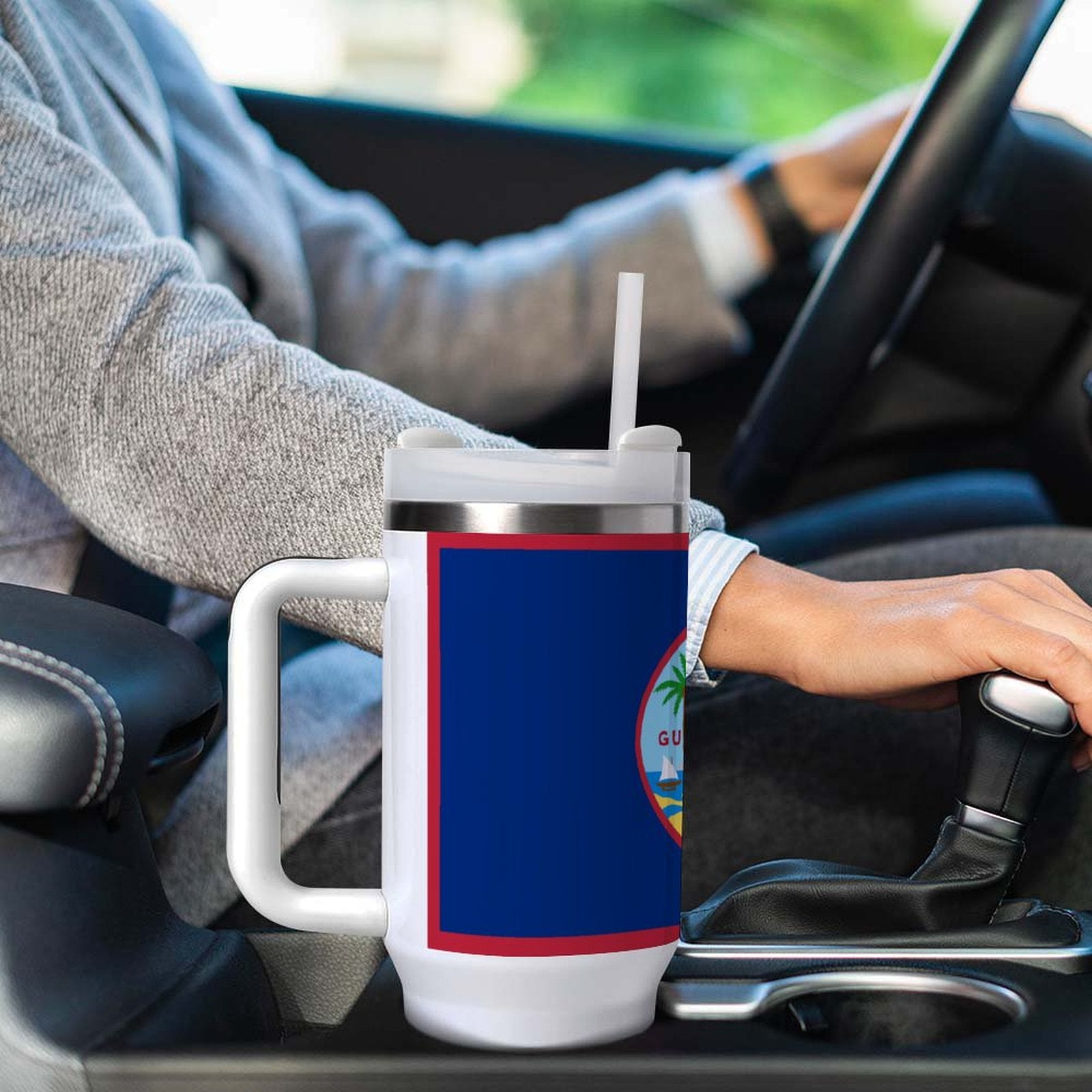 Person driving car holding [Brand] travel mug with straw.