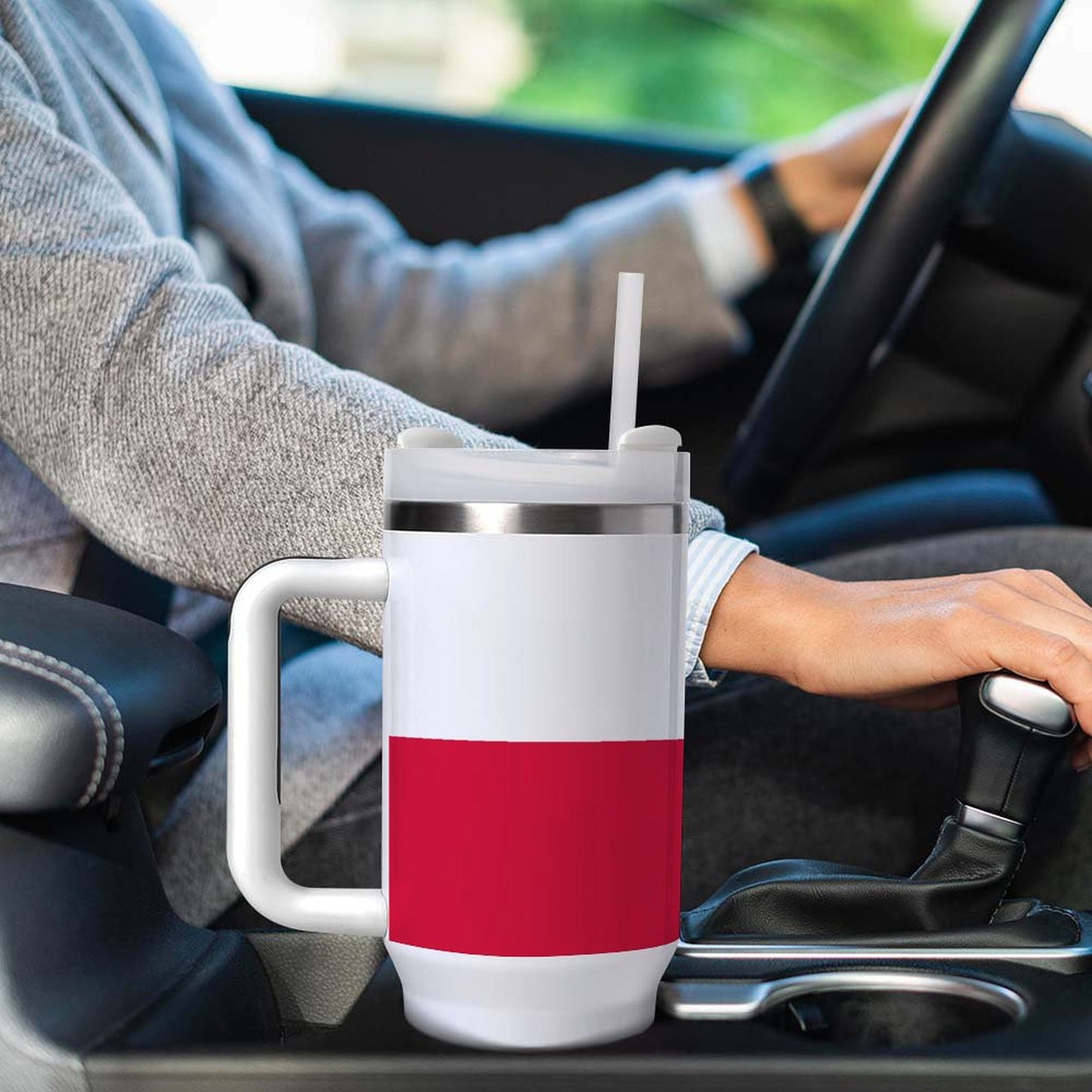 Person driving with [Brand] red and white mug nearby.