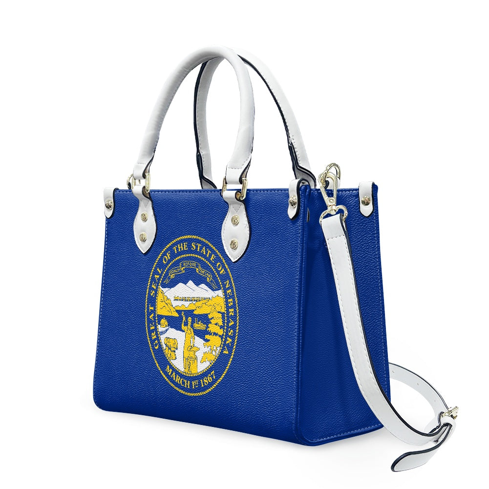 Blue handbag with Nebraska state seal, white handles, [Brand].