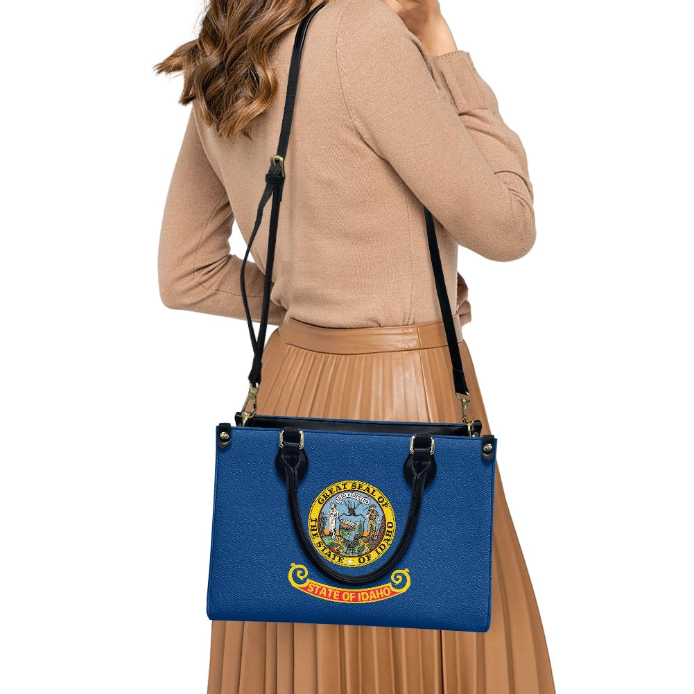 Woman carrying [Brand] blue handbag featuring Idaho state seal.