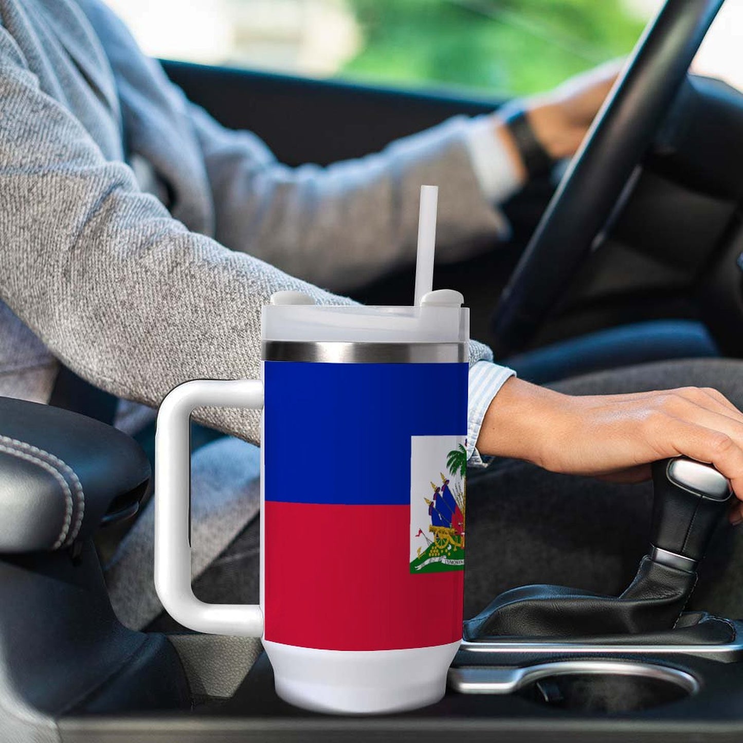 Man driving car with [Brand] Haiti flag travel mug.