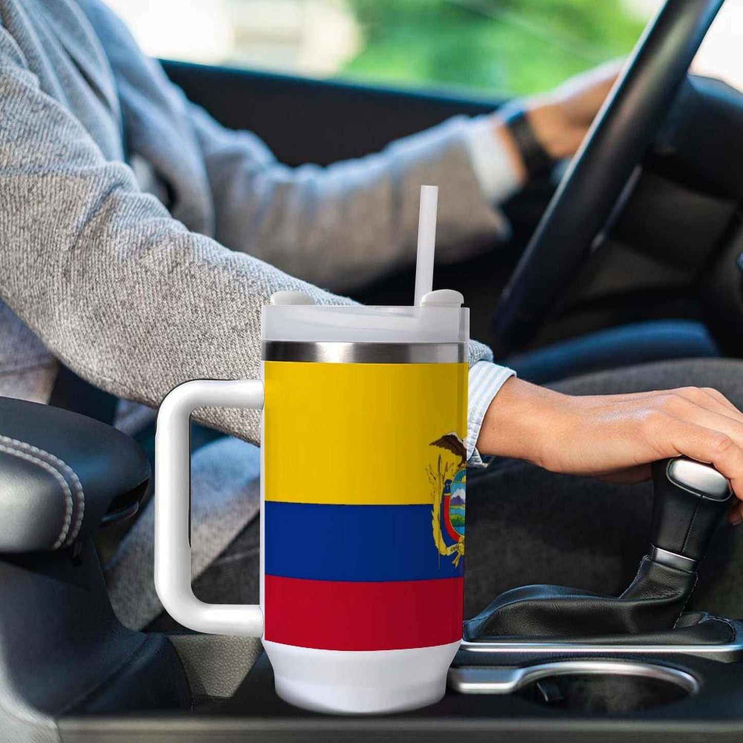 A person drives car holding [Brand] cup with flag design.
