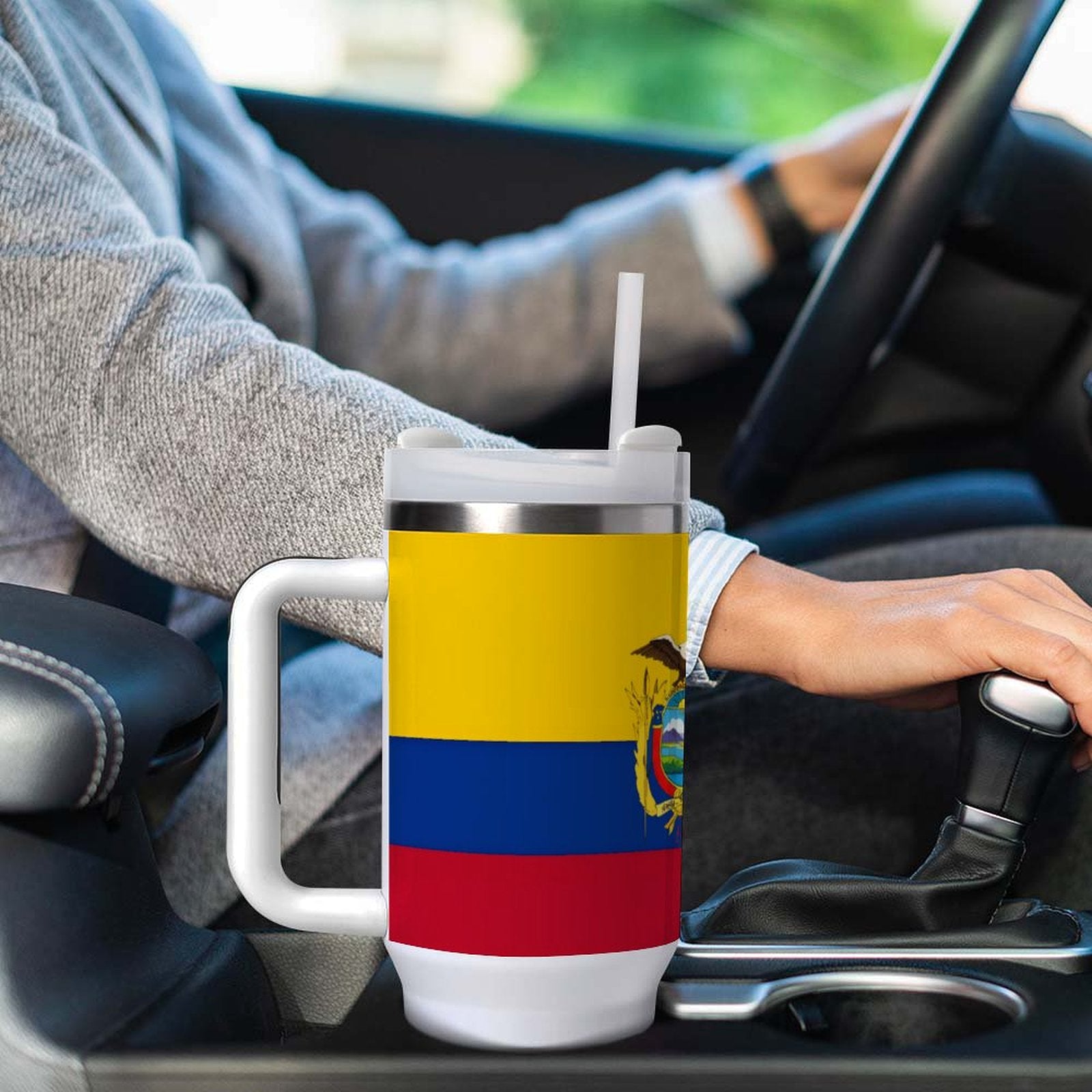 A person drives car holding [Brand] cup with flag design.
