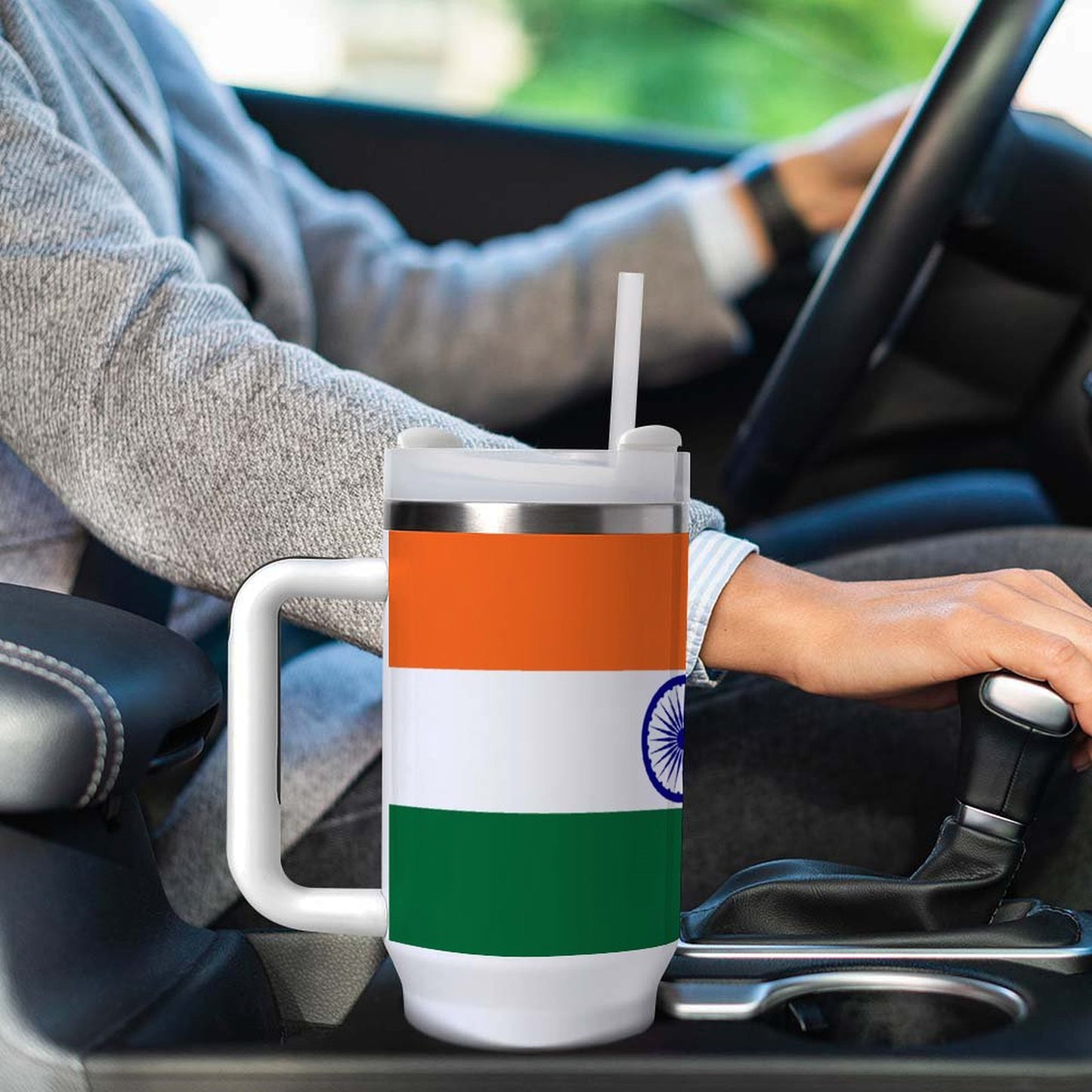 Person driving with [Brand] travel mug displaying Indian flag.