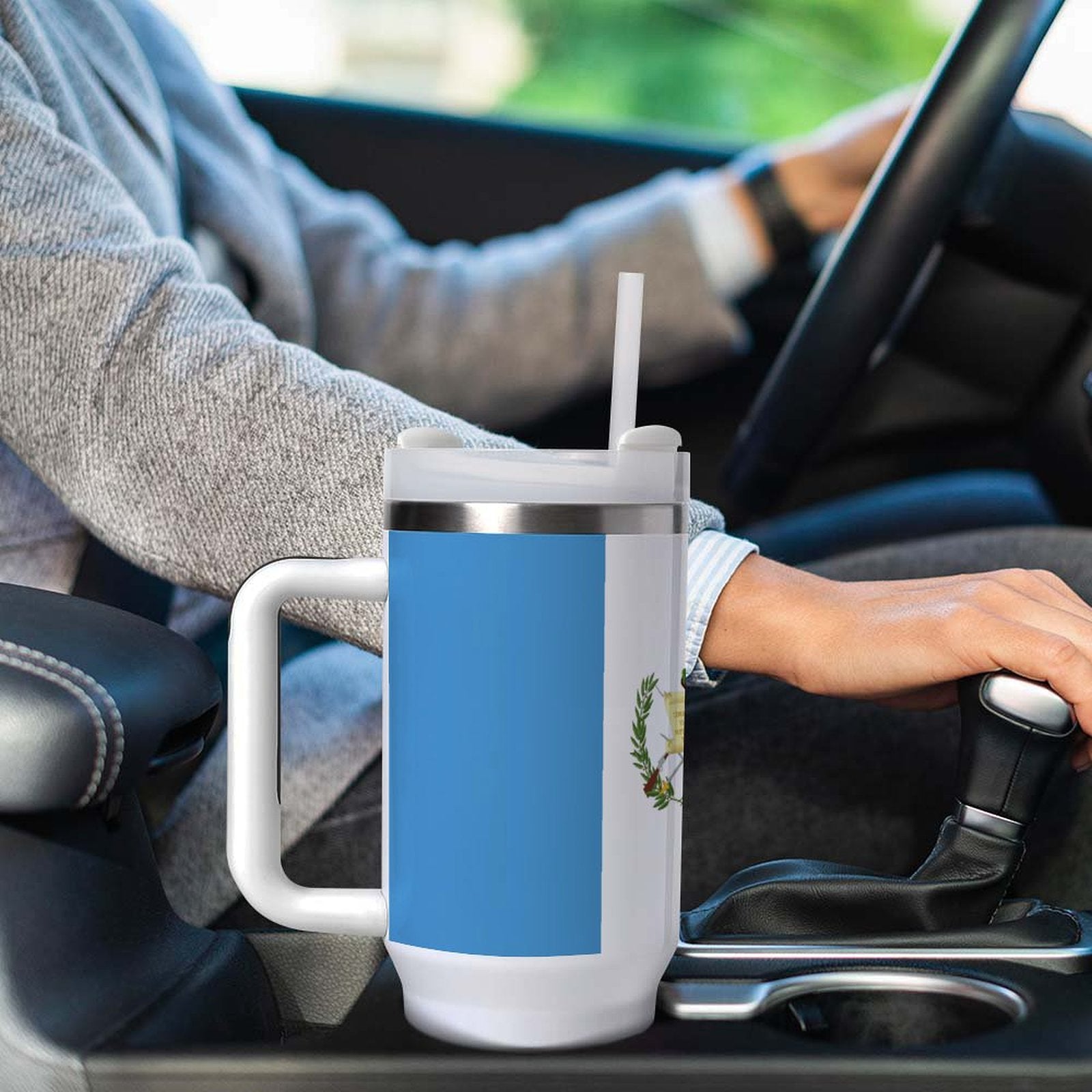 Sweatered driver with [Brand] mug, straw, in car console.