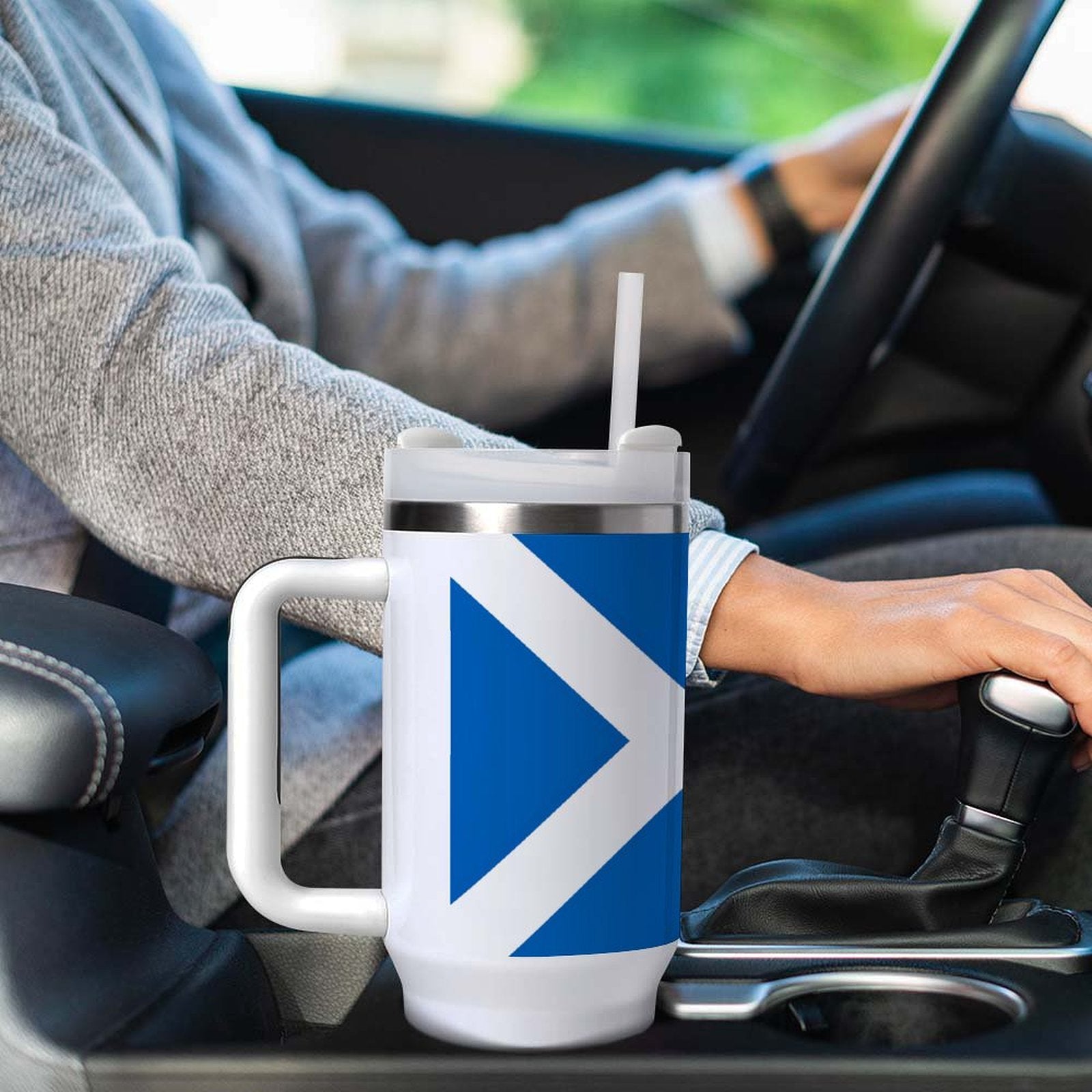 Driver holding [Brand] travel mug with blue geometric design.